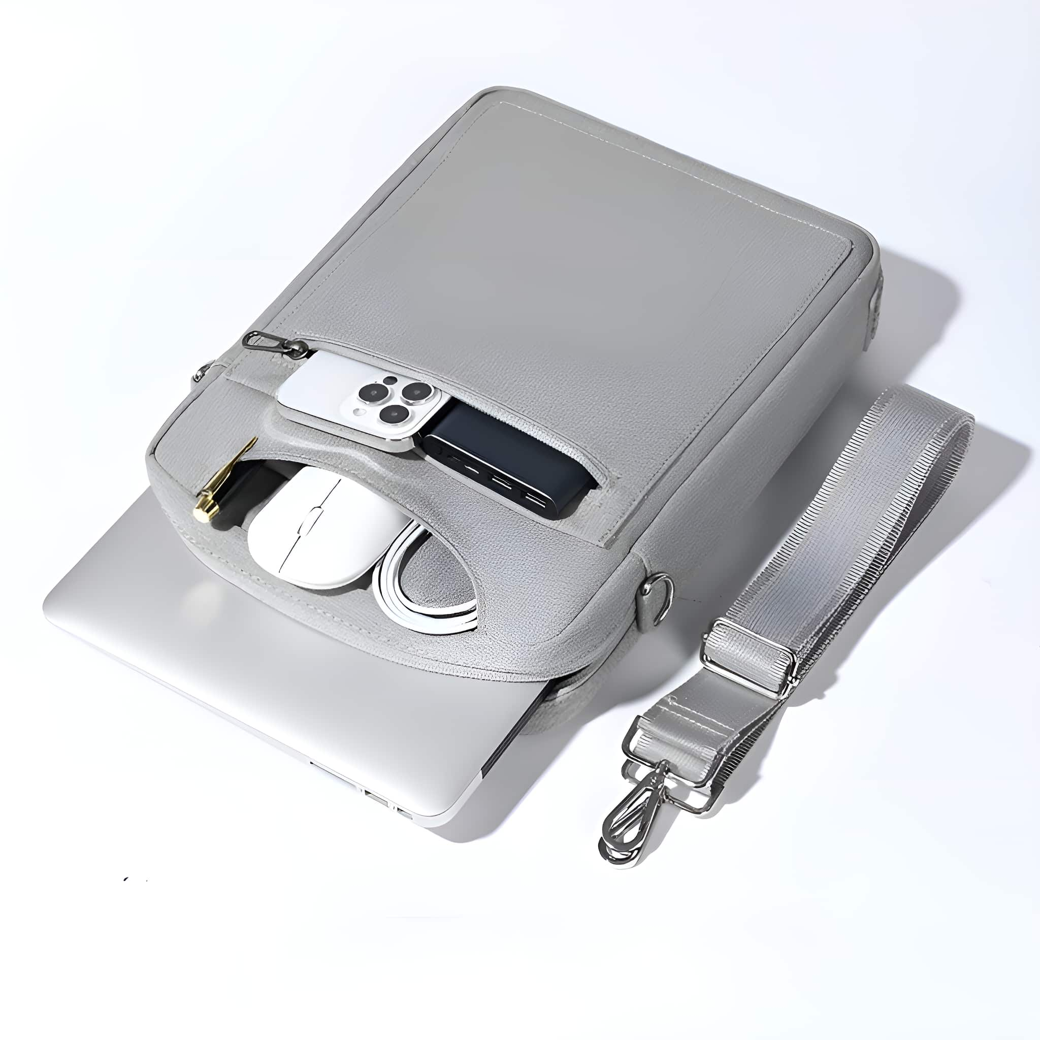 Graue Tasche geöffnet, zeigt Laptop, Telefon, Maus und andere Gegenstände.