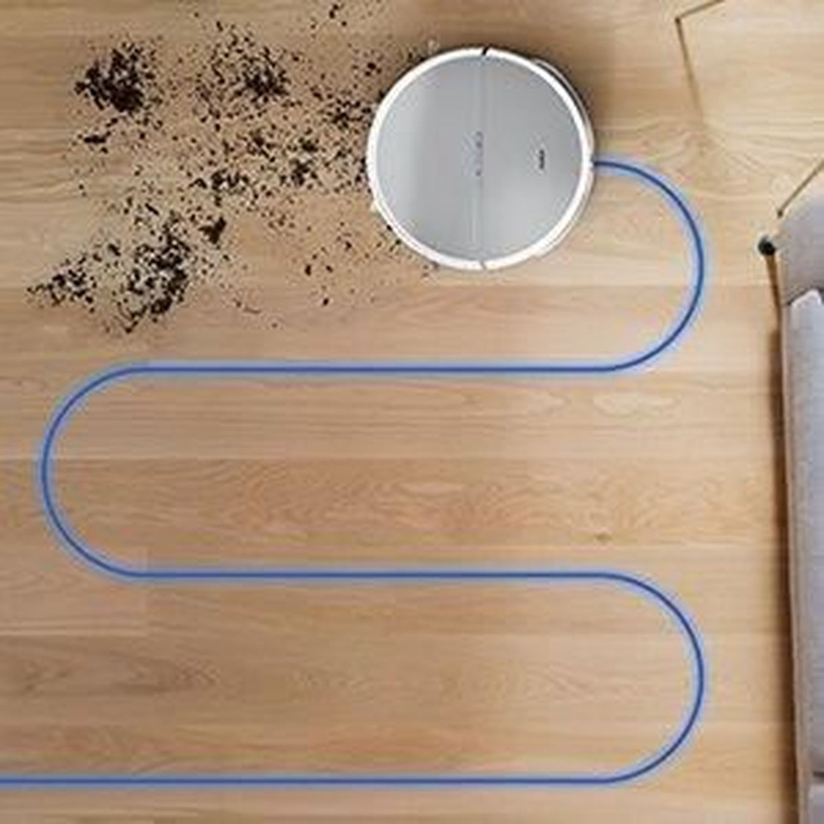 Odkurzacz automatyczny na drewnianej podłodze z brudem. Odkurzacz podąża niebieską trasą.