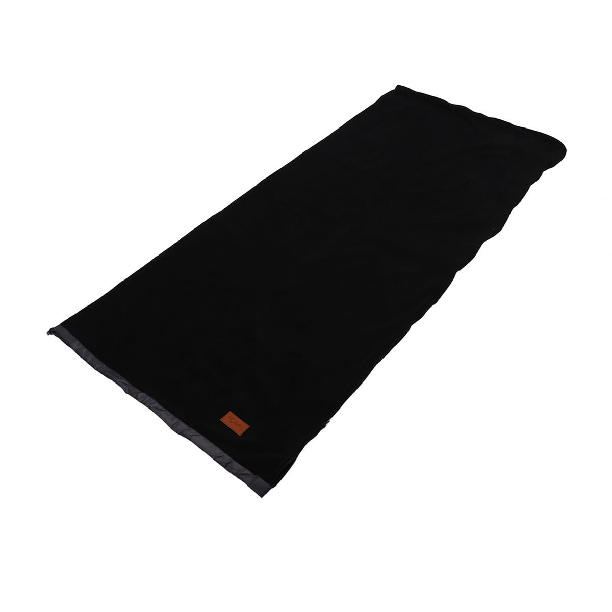 Schwarzer Schlafsack aufgerollt, mit einem kleinen braunen Etikett. Es ist eine flache Ablage.