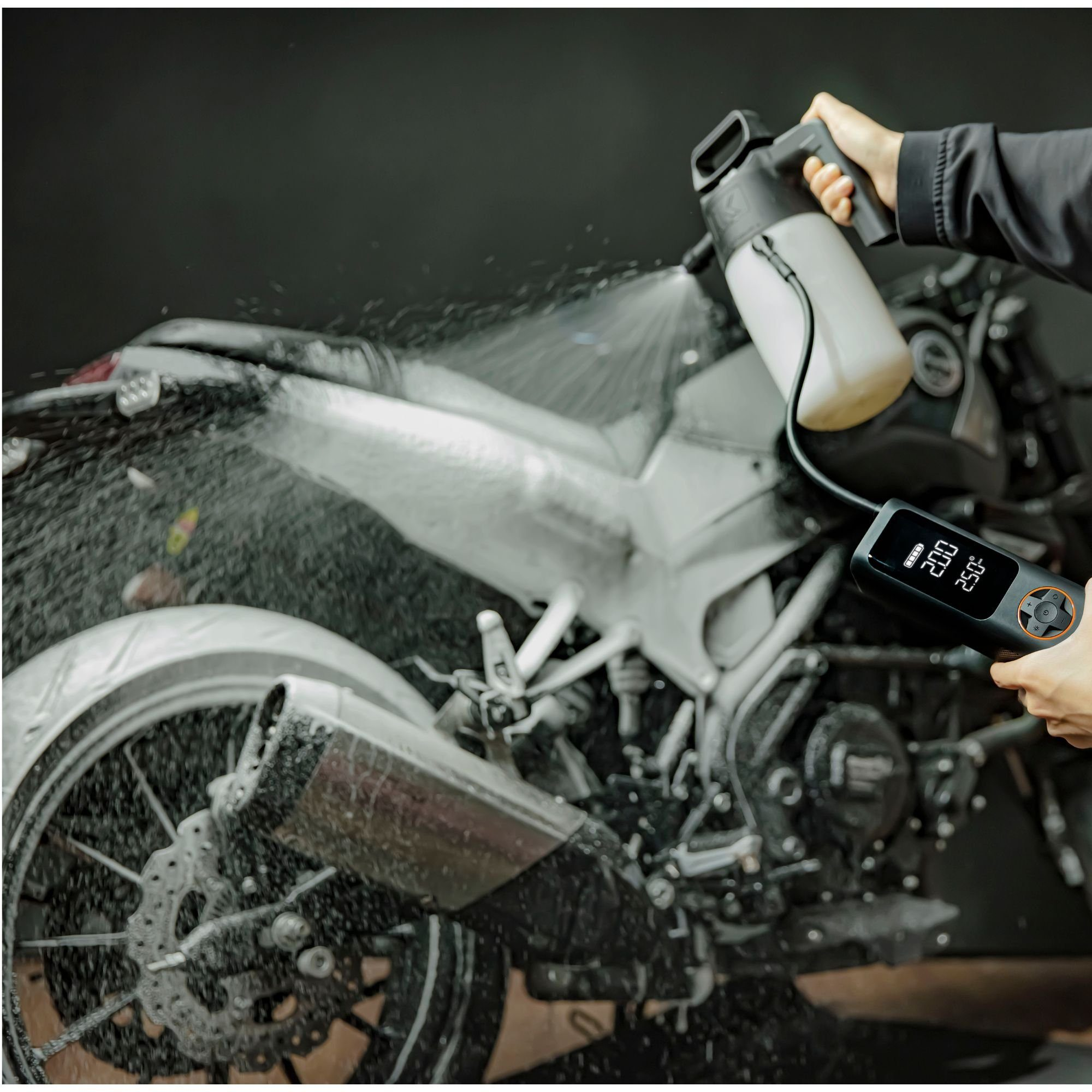 Eine Person besprüht ein Motorrad mit einem schwarz-weißen Sprayer und einem Bedienfeld.