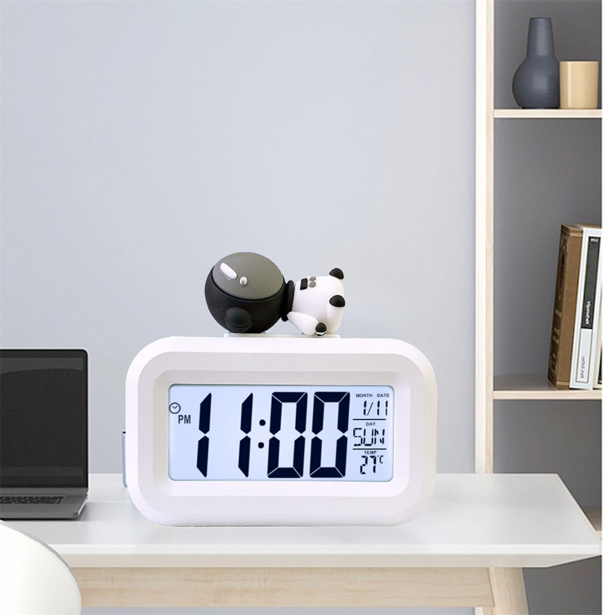 Ein weißer digitaler Wecker mit einem Panda oben, der 11:00 Uhr und das Datum anzeigt.