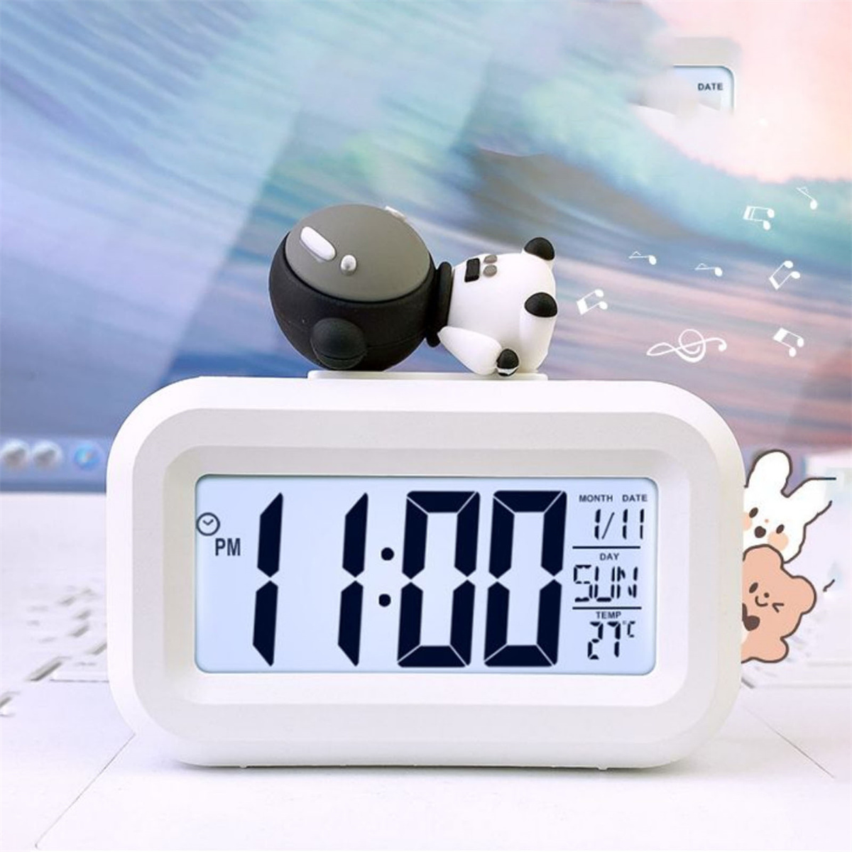 Weißer digitaler Wecker mit Panda-Figur. Zeigt 11:00 Uhr, Sonntag, 27°C und das Datum.