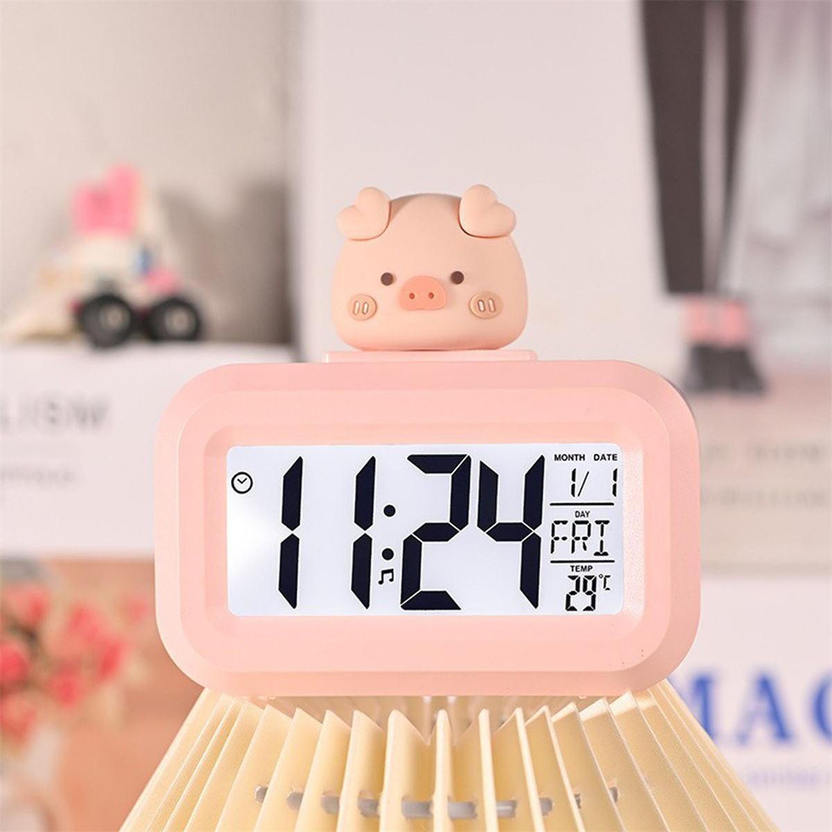 Rosa Schweineförmiger digitaler Wecker mit Zeit, Datum und Temperatur, auf Holzoberfläche.