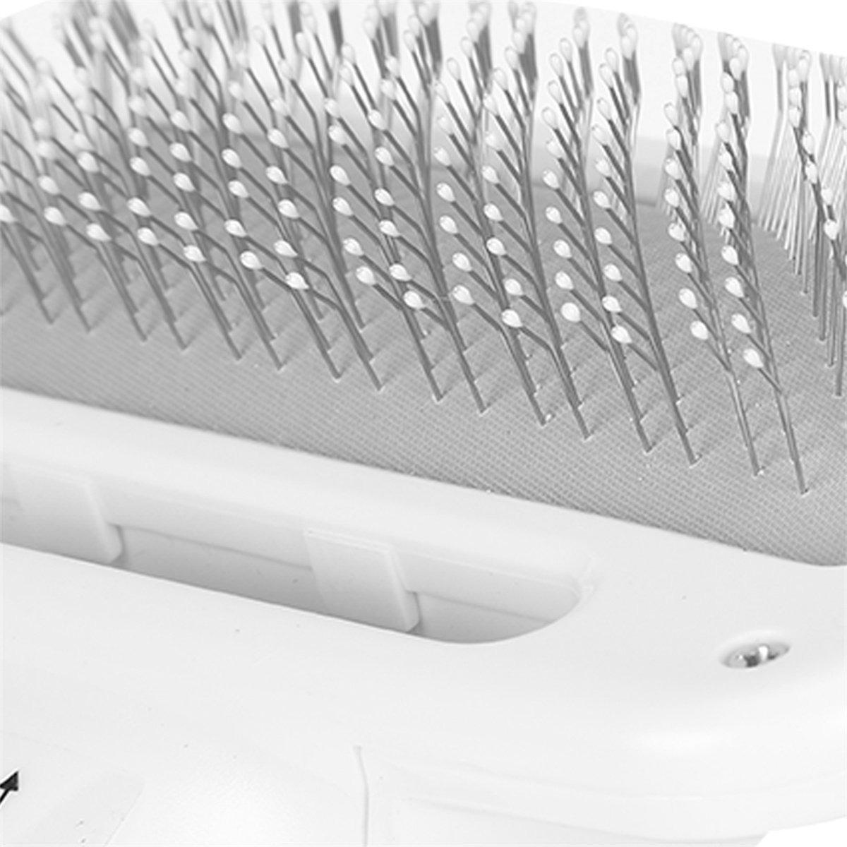 Nahaufnahme einer weißen Haustierbürste mit Metallborsten. Die Bürste hat ein gebogenes Design.