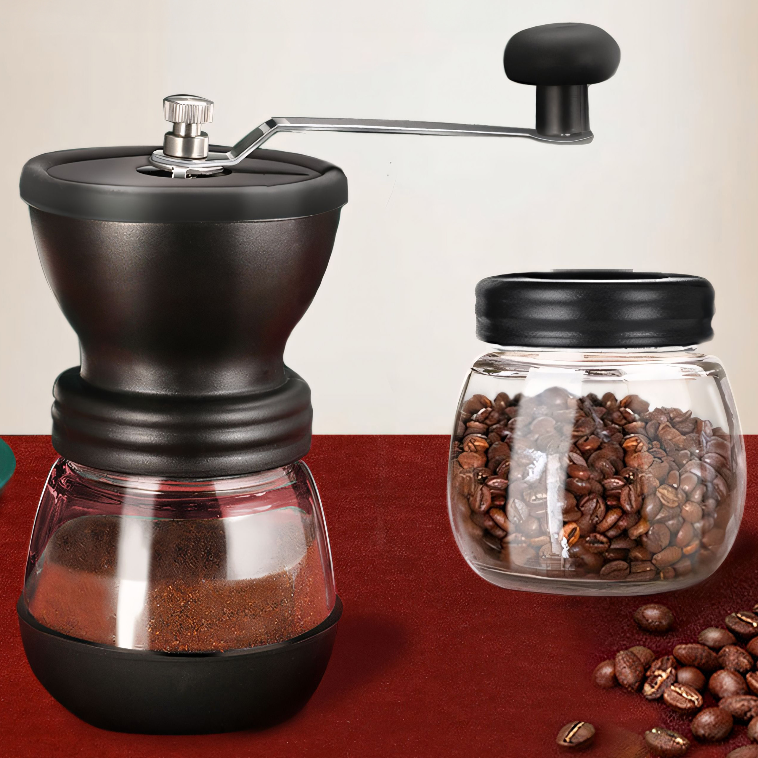 Macinacaffè manuale con corpo nero e barattolo di vetro con chicchi e caffè macinato.