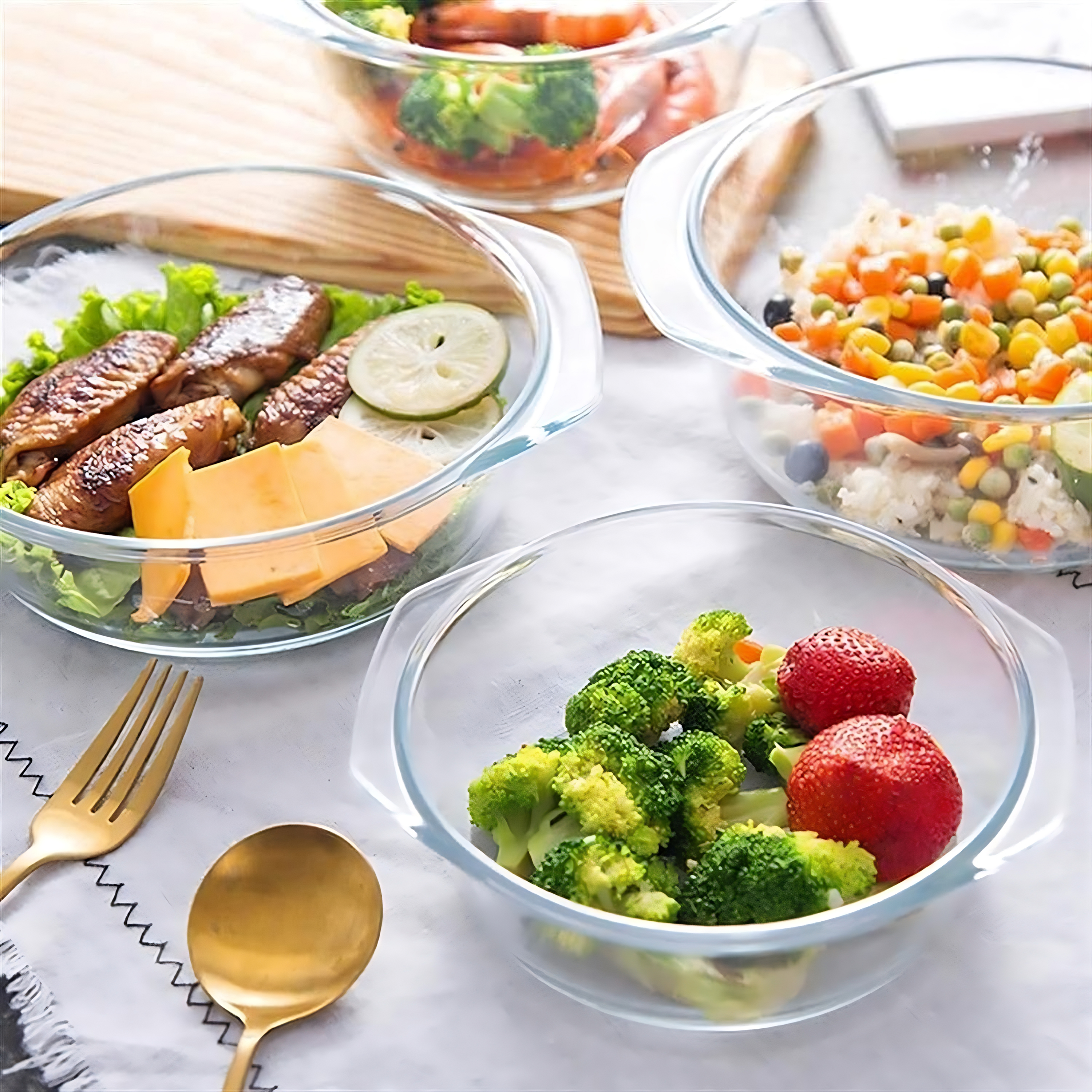 Glasschalen mit Essen: Brokkoli, Erdbeeren und eine Platte mit Hühnchen und Gemüse.