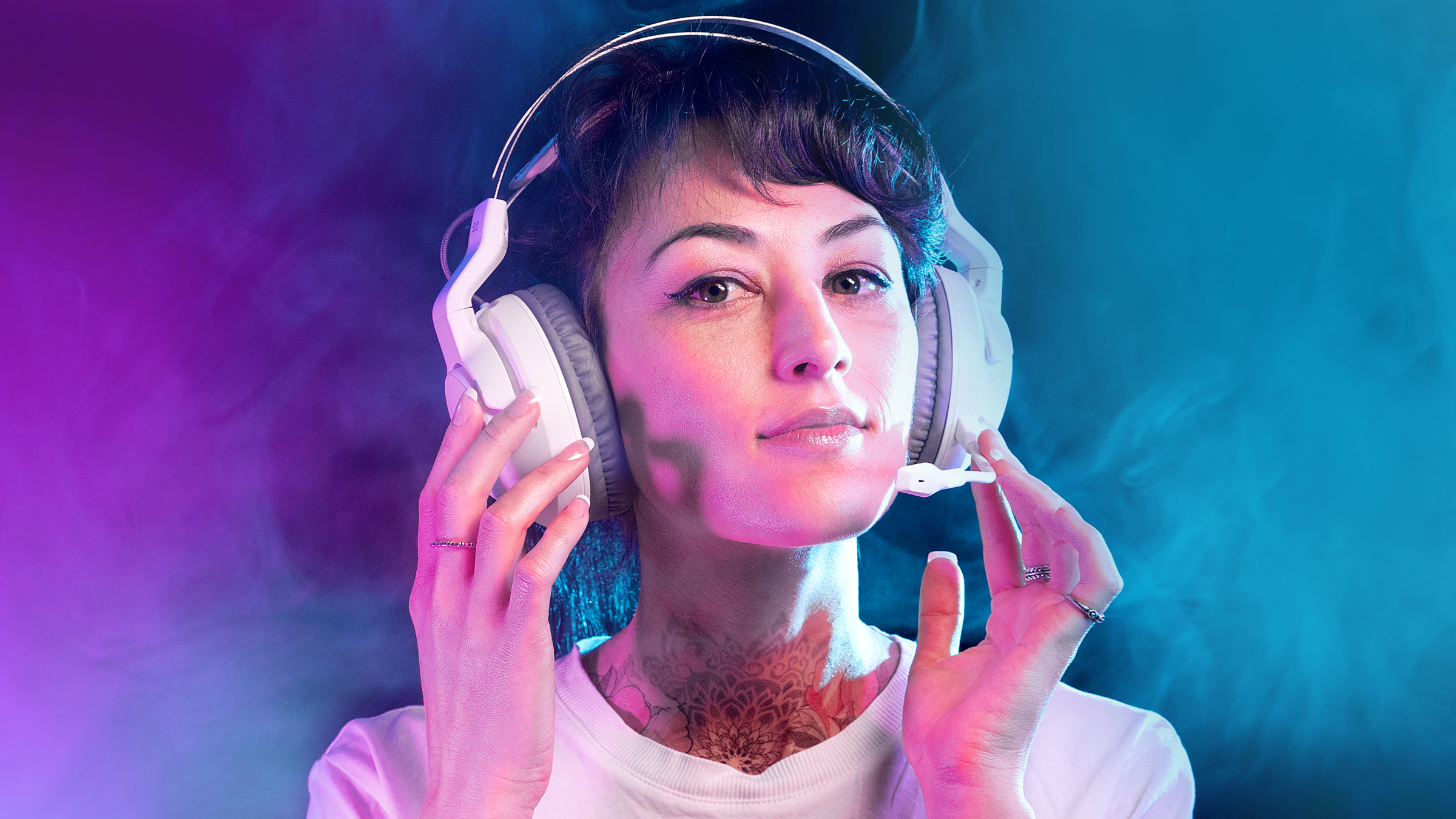 Kobieta w białych słuchawkach, trzyma je. Różowe i niebieskie światła w tle z dymem.