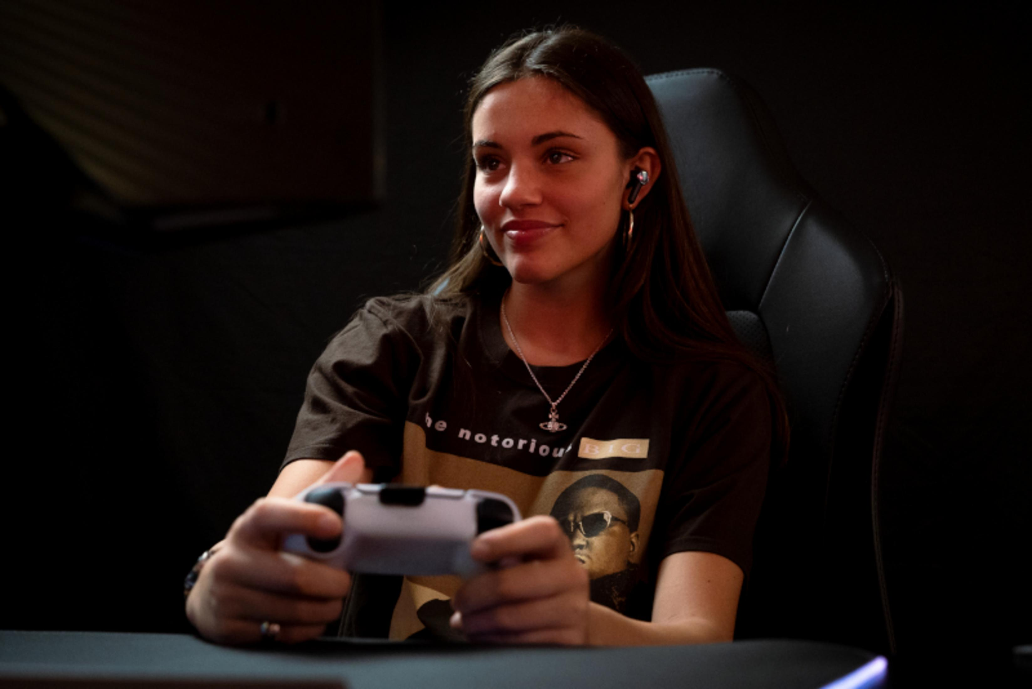 Kobieta gra w grę z kontrolerem. Ma na sobie słuchawki.