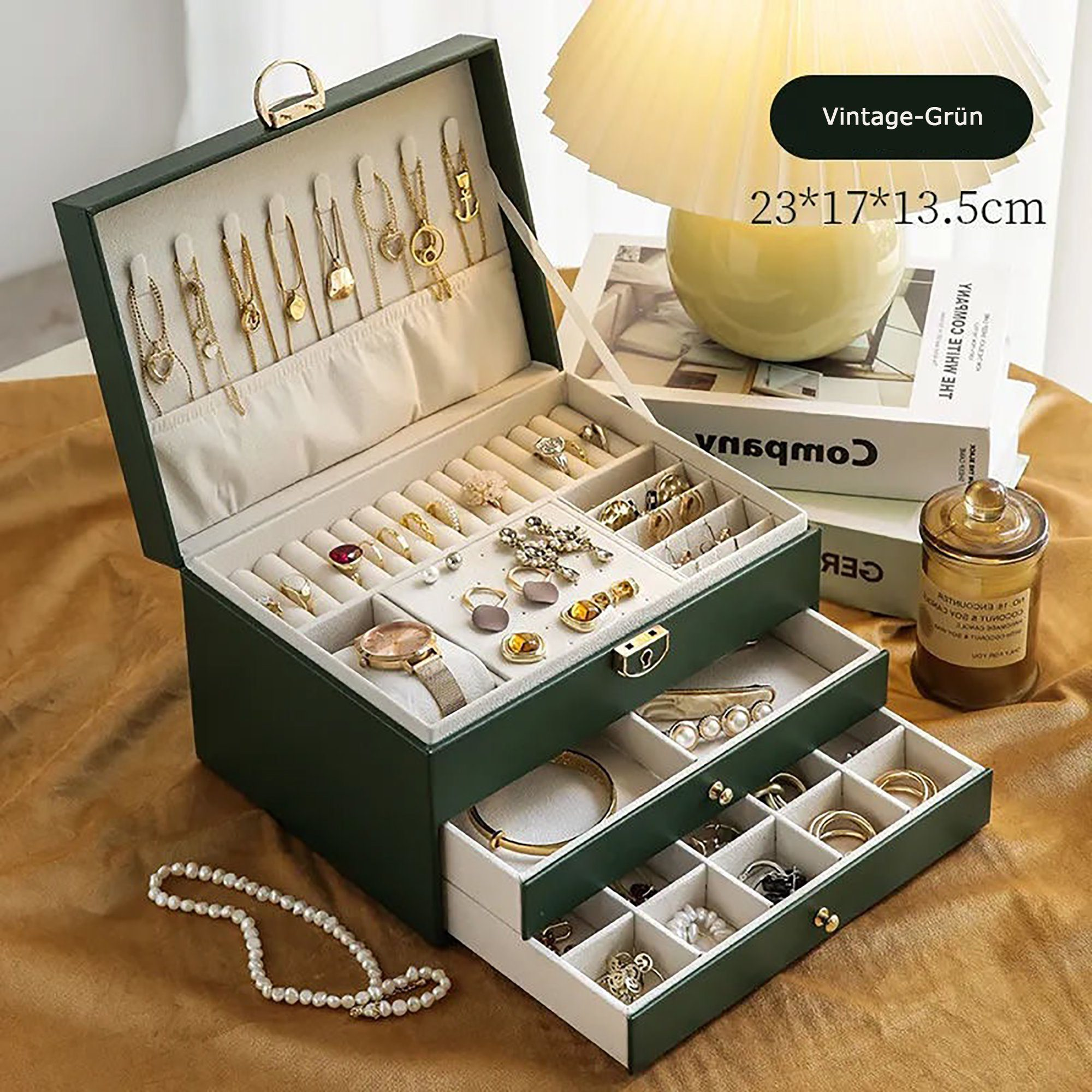 Geöffnete Schmuckschatulle, gefüllt mit Schmuck. Grüne Box, mehrere Fächer, goldene Halsketten, Ringe und eine Uhr.