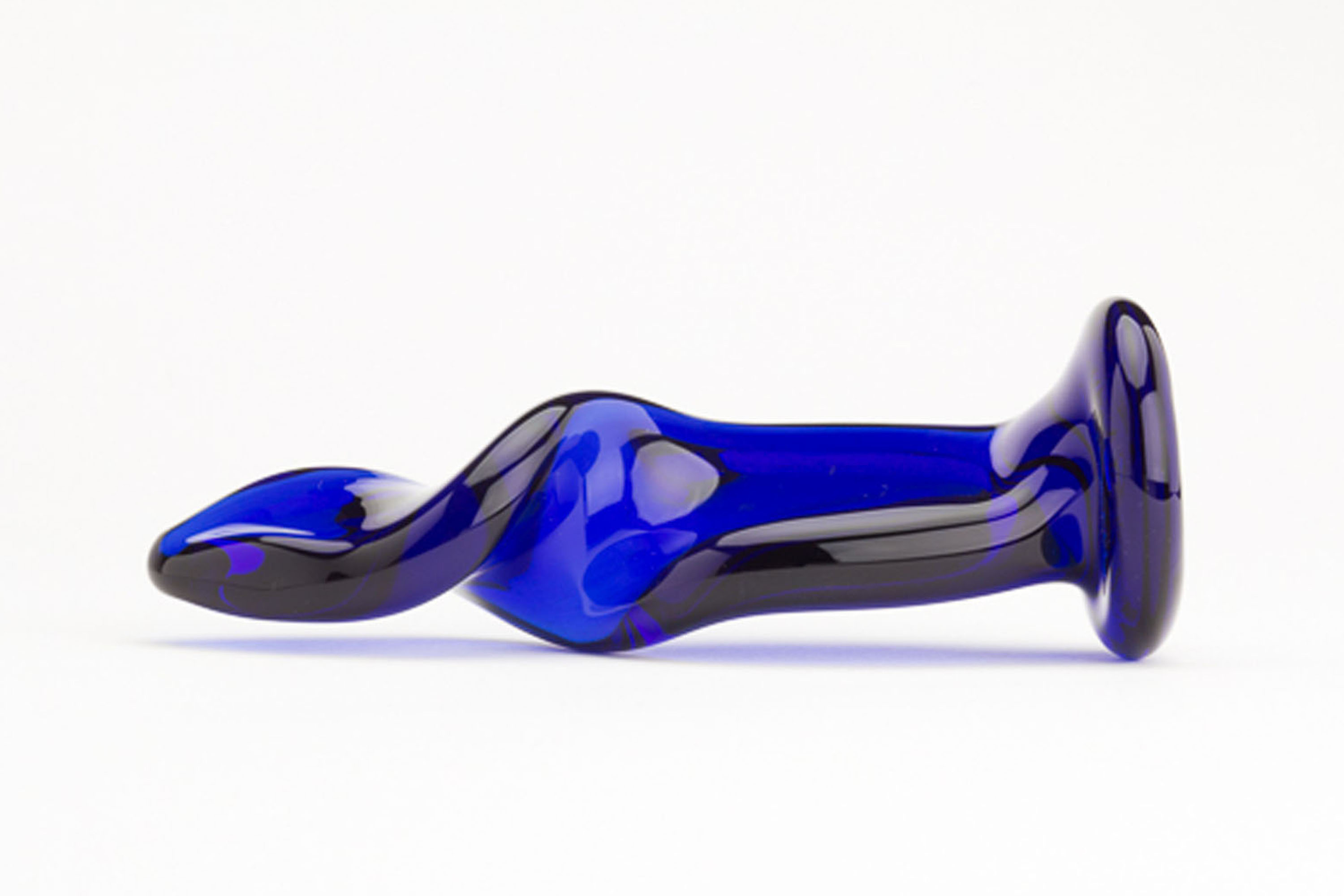 Ein blaues Sexspielzeug aus Glas mit geschwungenem, glattem Design, liegend auf weißem Hintergrund.