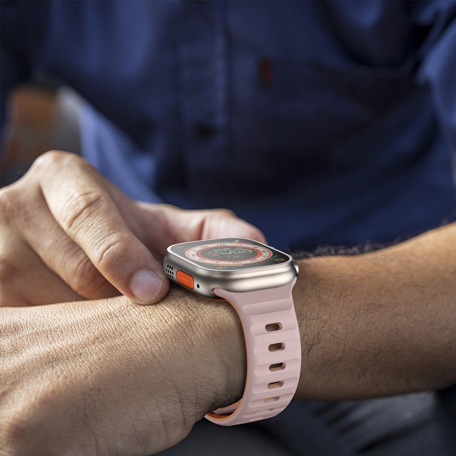 Handgelenk mit Smartwatch. Die Uhr hat ein rosa Armband und orangefarbene Akzente.