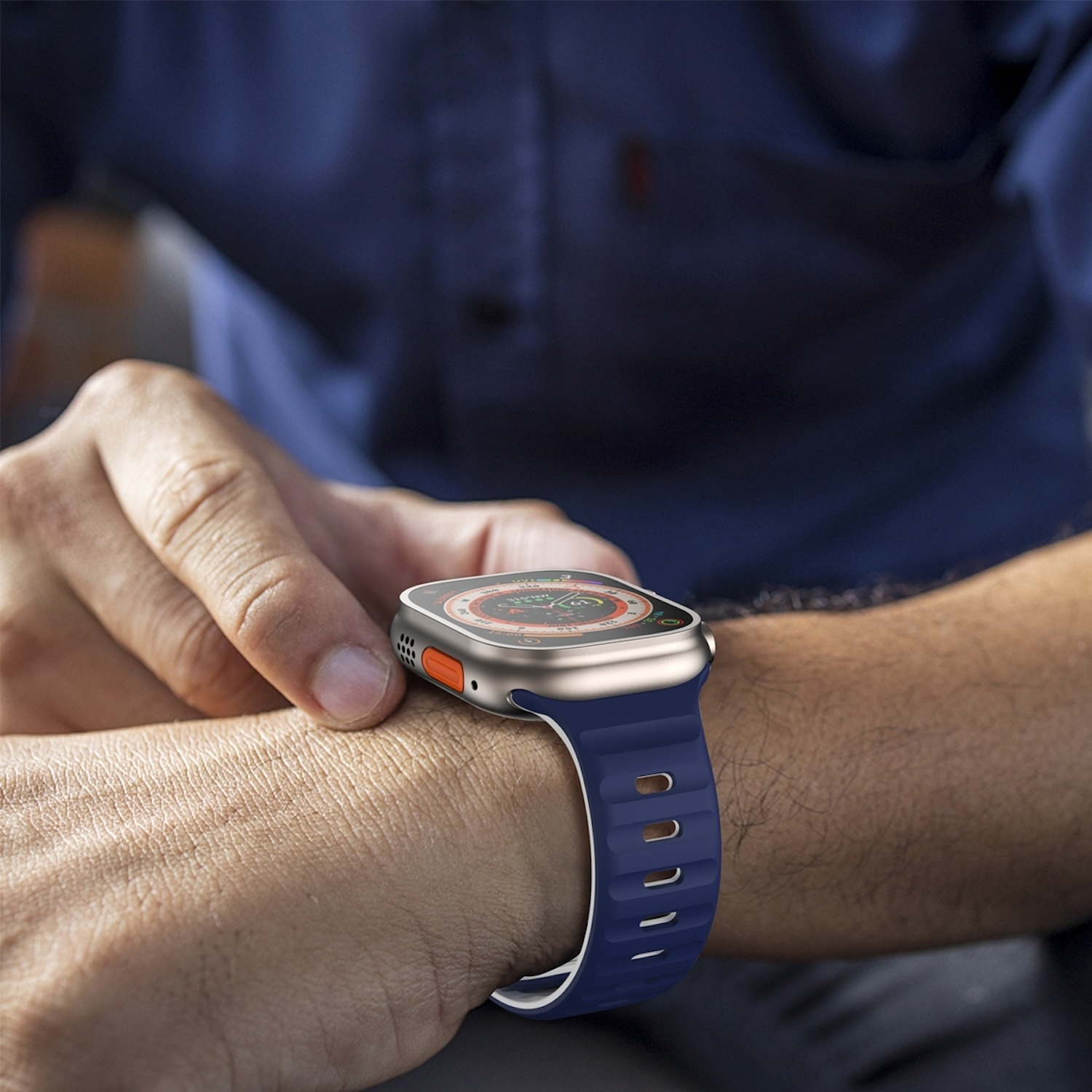Eine Hand berührt eine Smartwatch mit blauem Armband. Die Person trägt ein blaues Hemd.