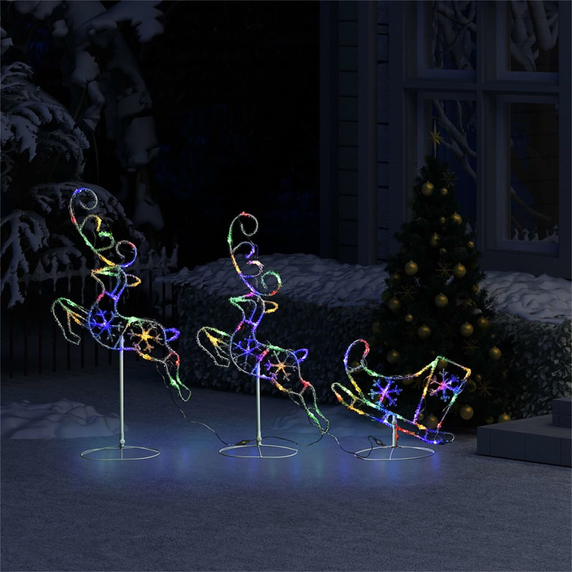 Weihnachtsszene mit drei beleuchteten Rentierdekorationen und einem Baum auf verschneitem Boden.