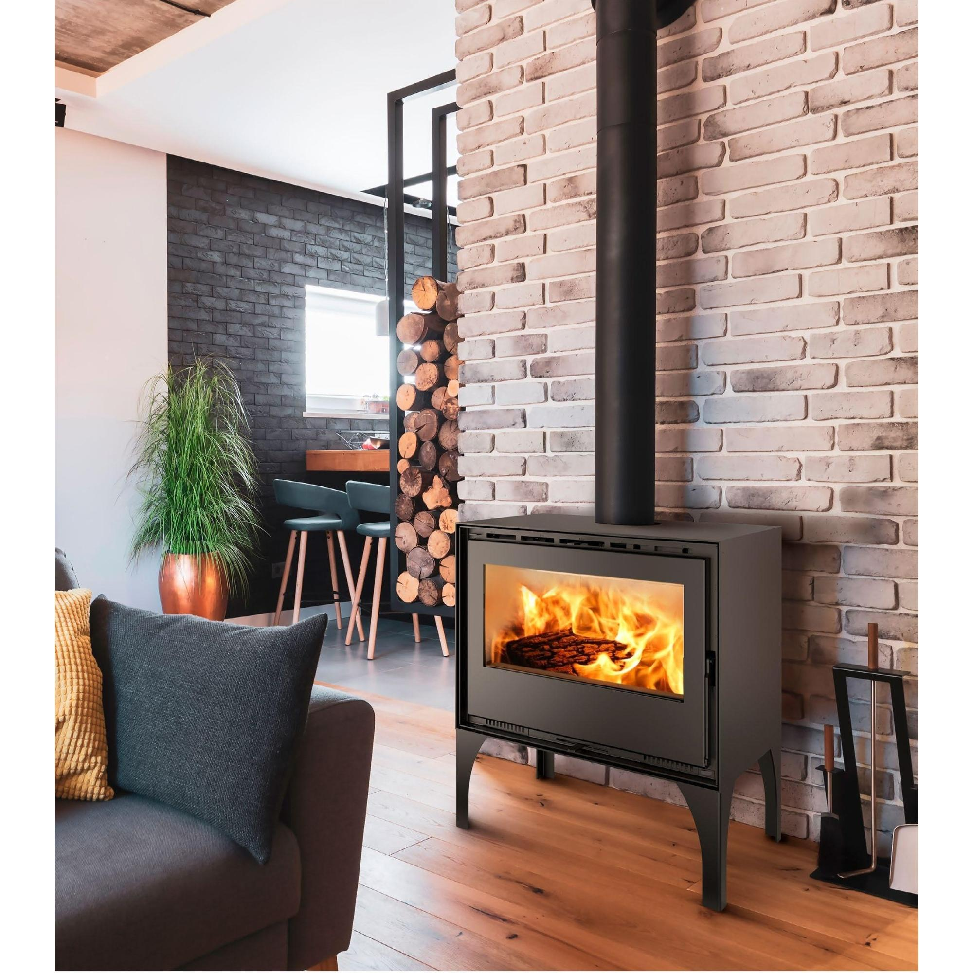 Chimenea con leños ardiendo, sofá gris y pared de ladrillo.