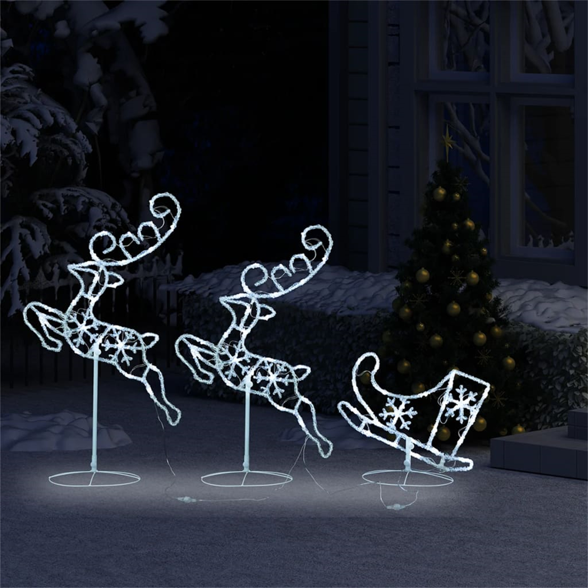 Weihnachtsdekoration im Freien: drei Rentiere und ein Schlitten mit Schneeflocken, alles in weißem Licht.