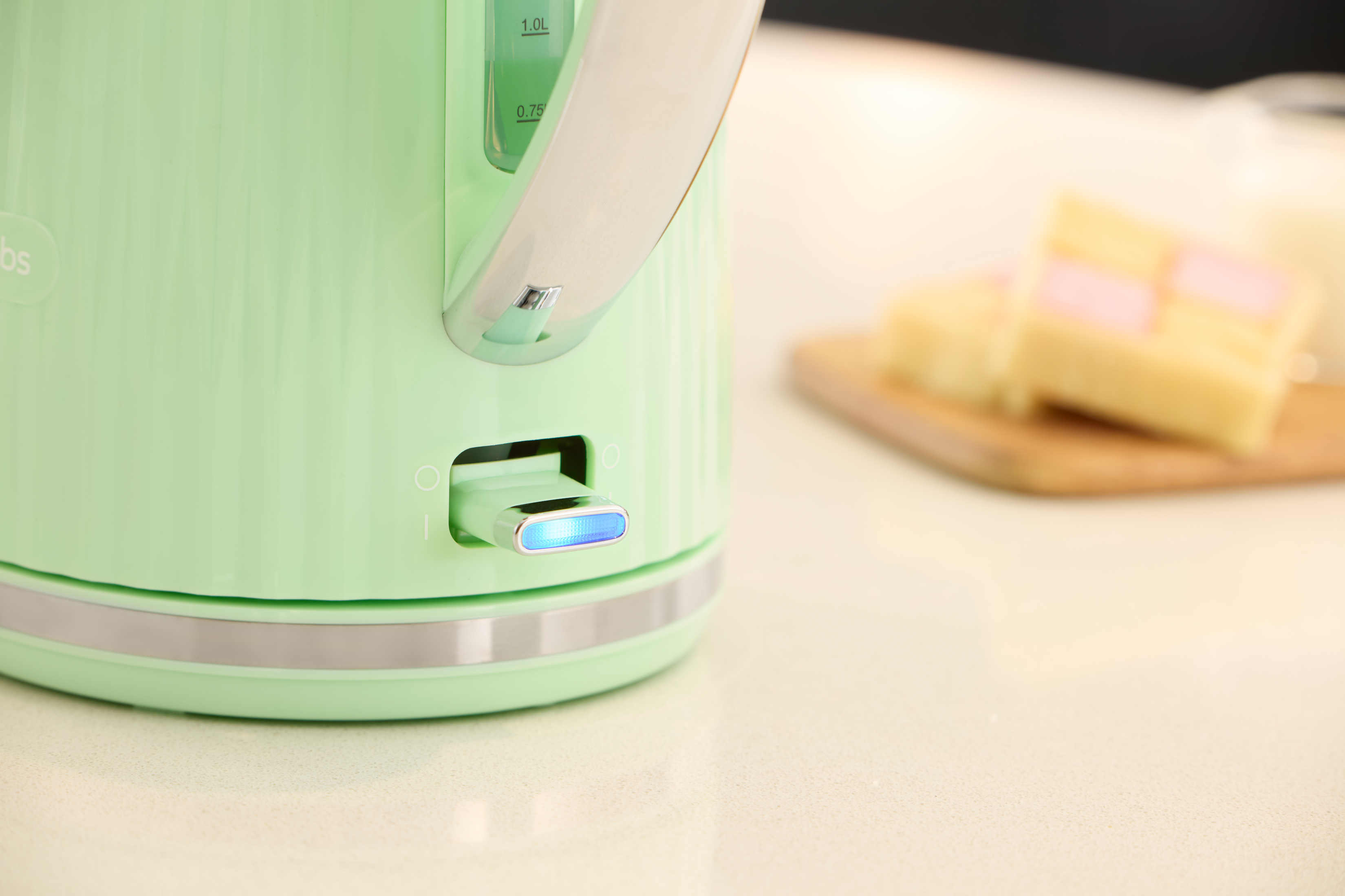 Primo piano di un bollitore elettrico verde menta con base e luce blu.