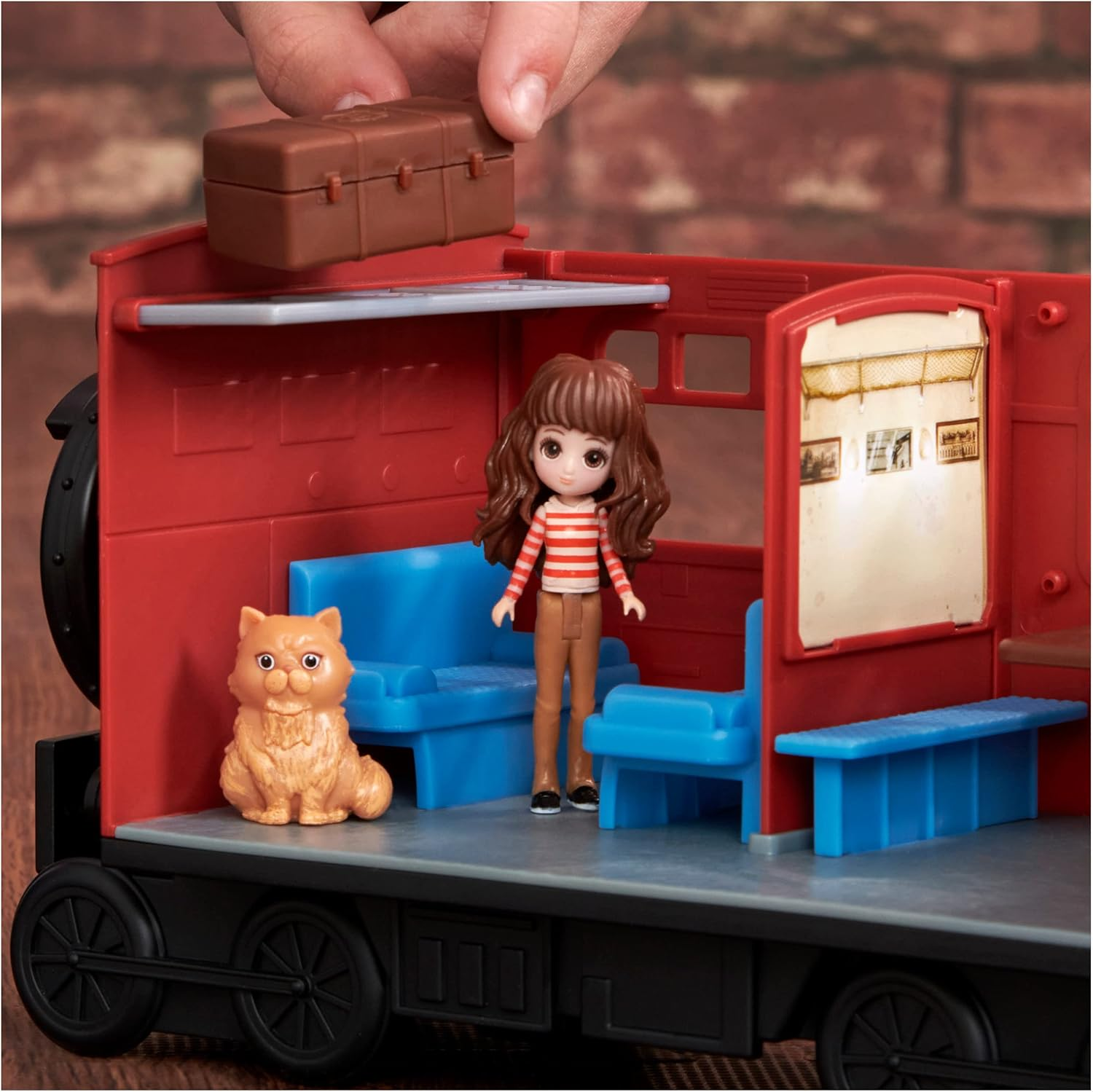 Wagonik kolejki z zabawką i kotem. Ręka osoby trzyma bagaż.