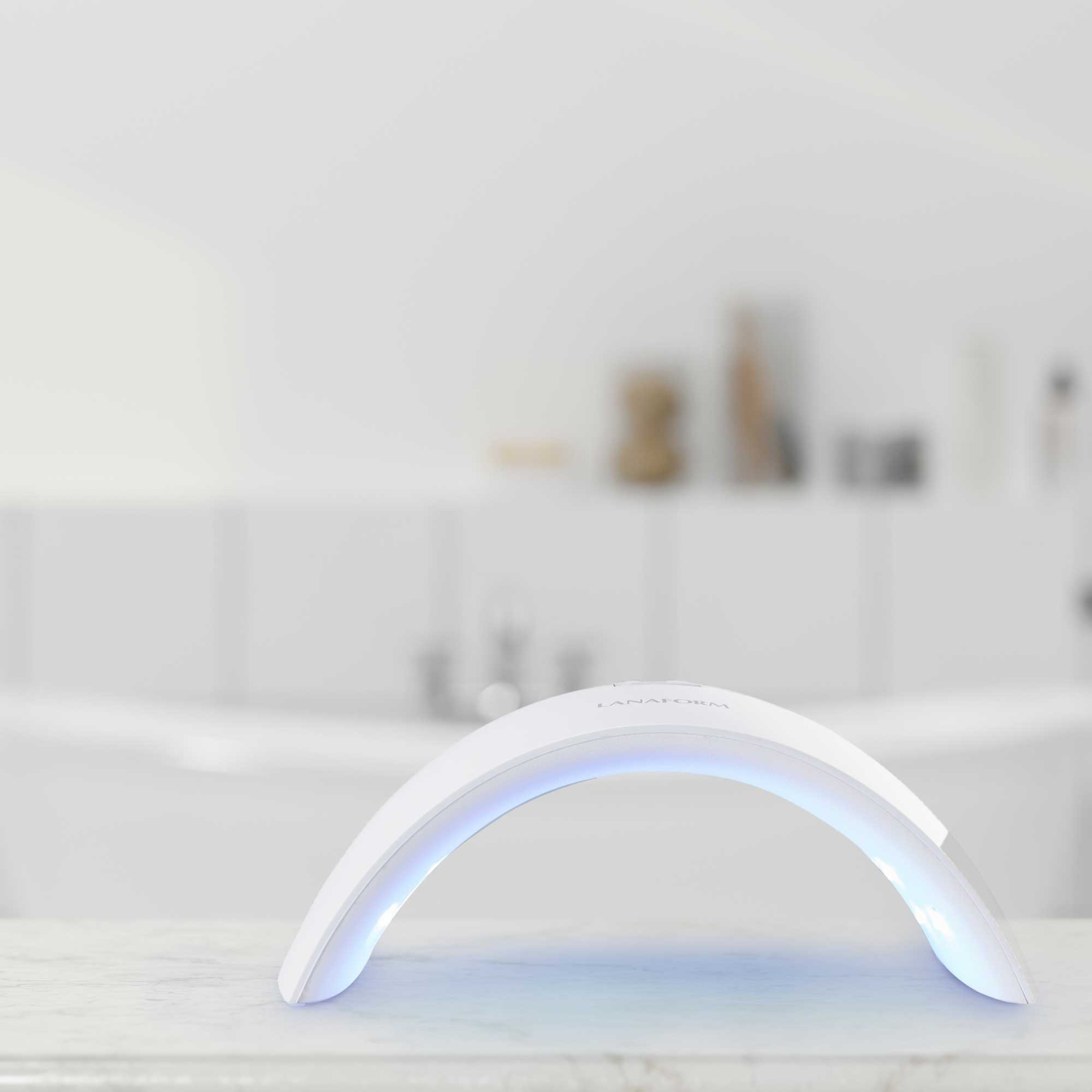 Weiße Nagelhärtungslampe auf weißer Oberfläche. Die Lampe ist gewölbt.