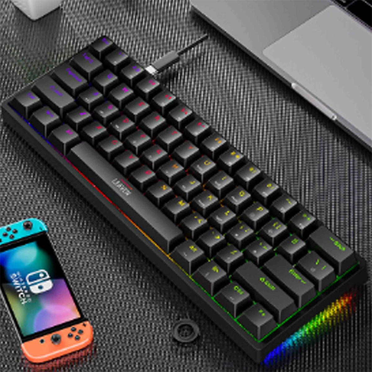 Schwarze Tastatur mit bunten Tasten, ein Telefon und ein Laptop. Schwarze Oberfläche.
