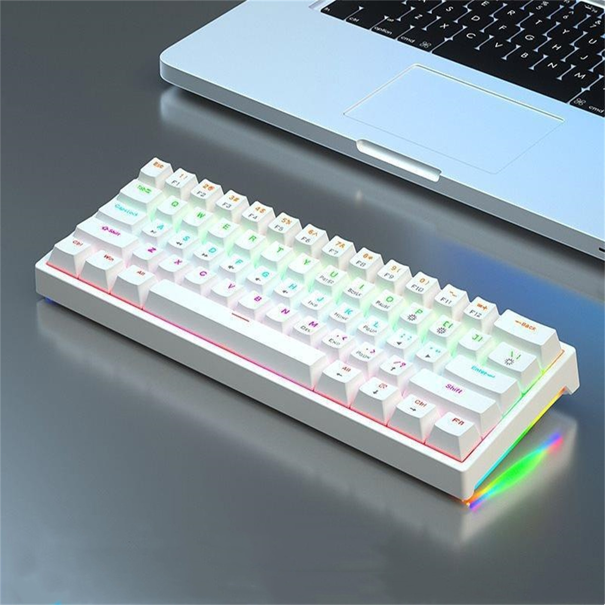 Weiße Tastatur mit farbiger Hintergrundbeleuchtung auf hellgrauer Oberfläche, neben Laptop.