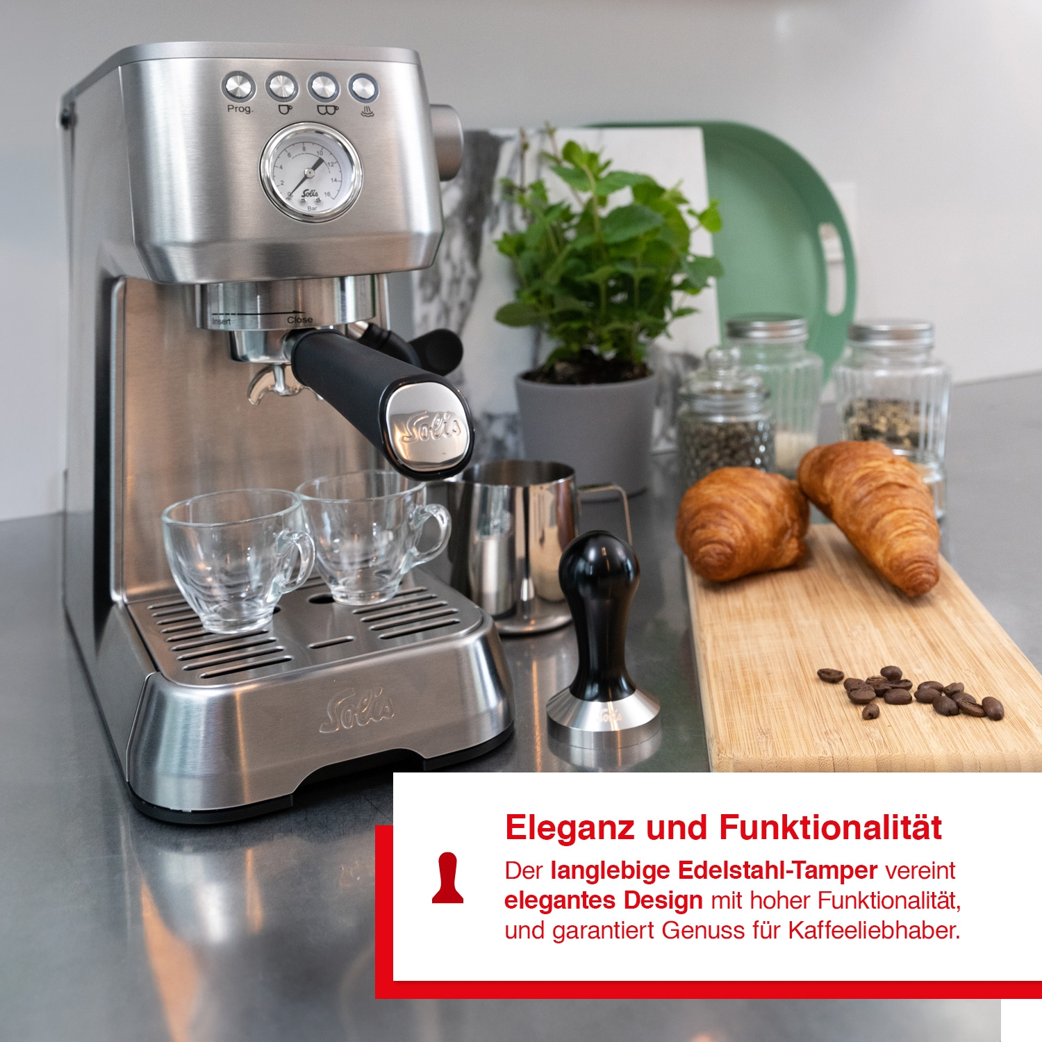 Eine silberne Espressomaschine mit Tassen, einem Tamper und Gebäck auf einem Holzbrett.
