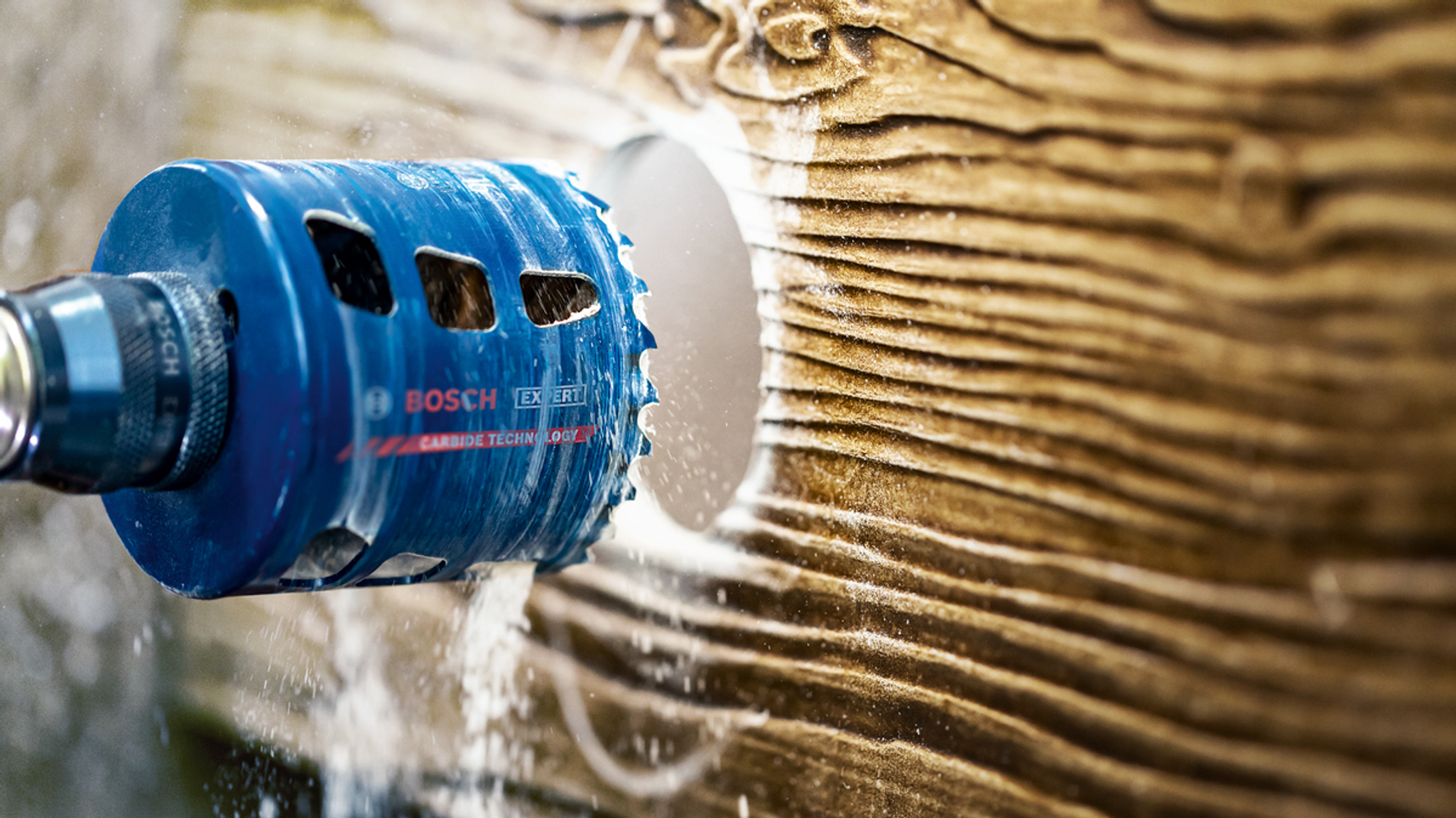 Niebieska piła otwornica wierci otwór w drewnie. Wióry są widoczne podczas cięcia drewna.