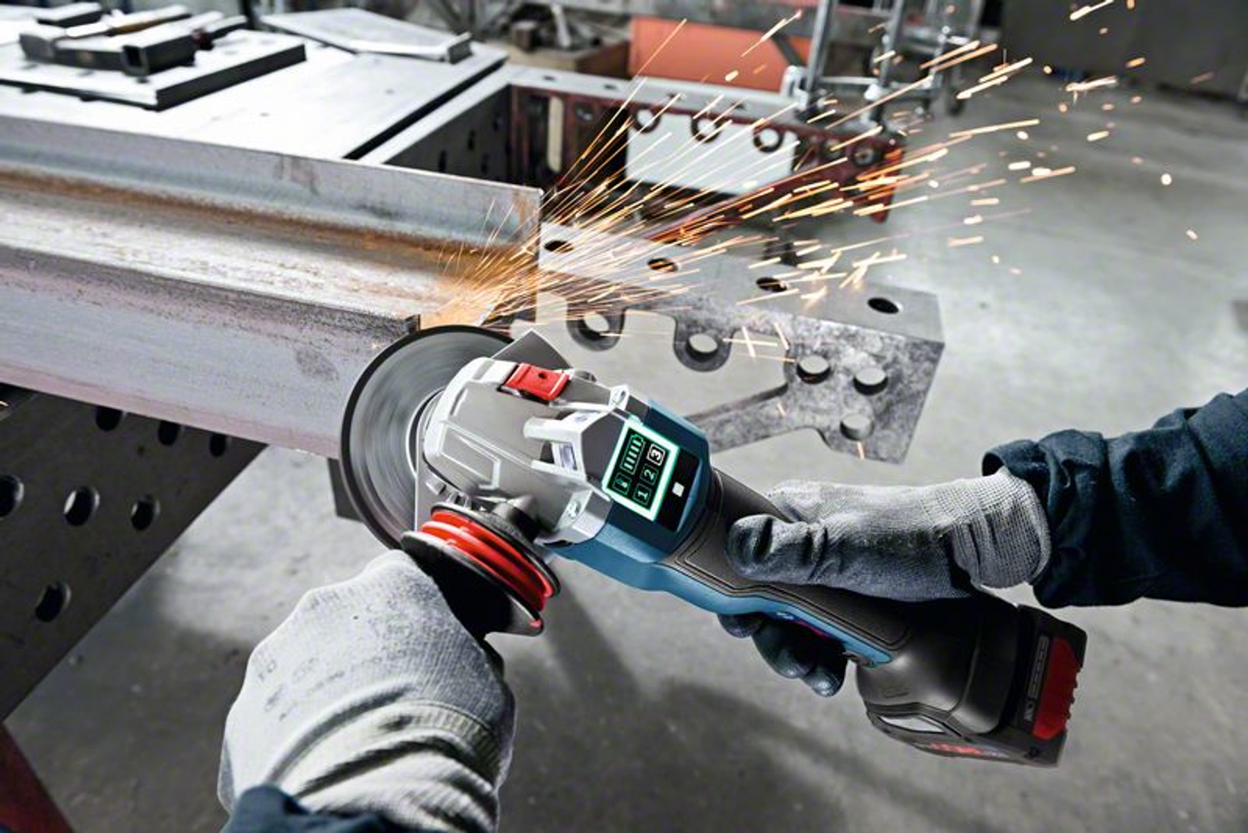 Osoba używa niebiesko-czarnej szlifierki kątowej, tworząc iskry na metalowym pręcie, w jasnym świetle.