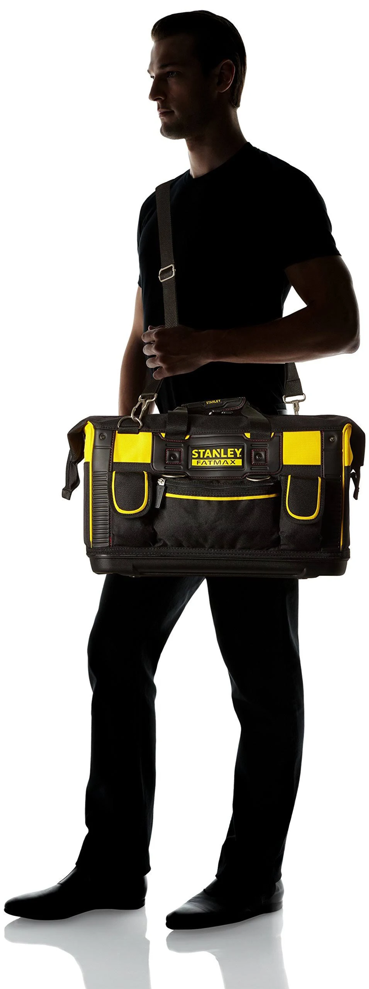 Uomo che trasporta una borsa portautensili Stanley nera e gialla. Sfondo bianco.
