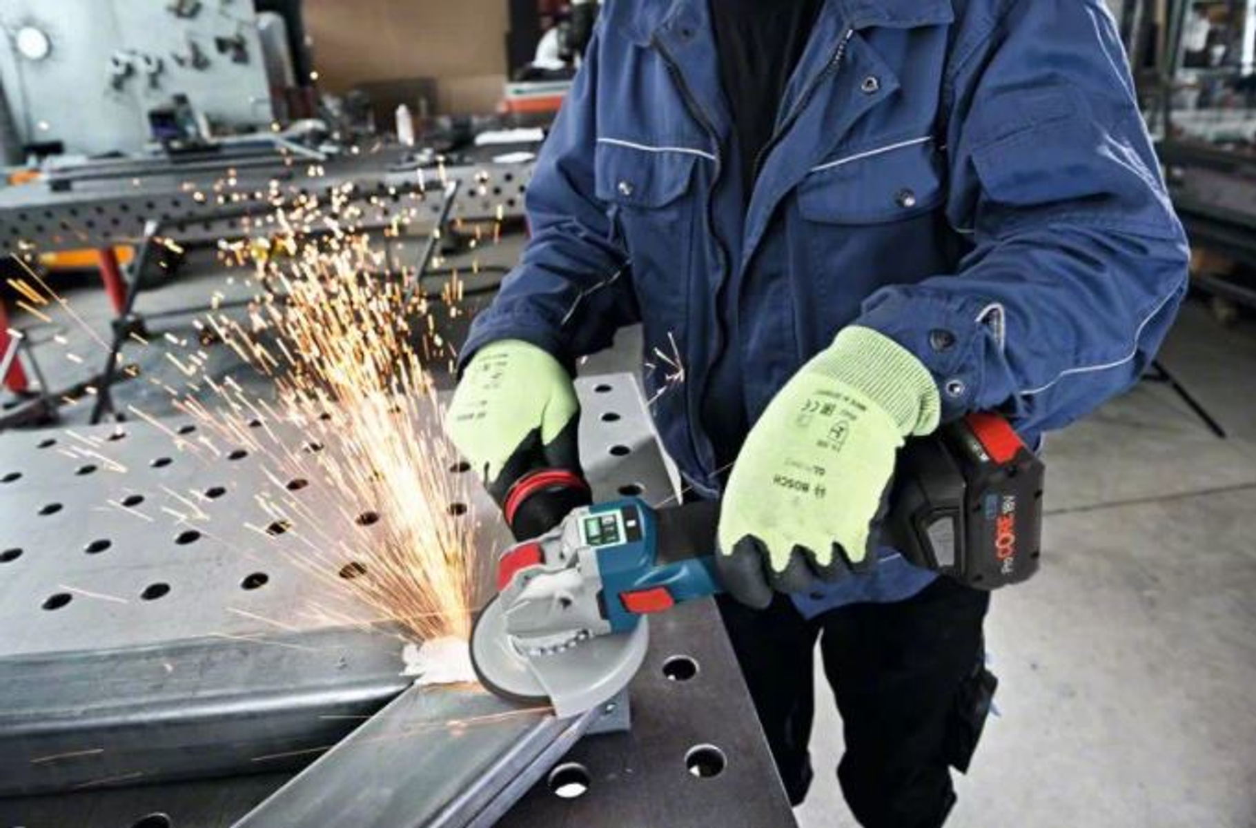 Osoba używająca szlifierki kątowej, iskry lecą, nosząca rękawice i sprzęt ochronny.