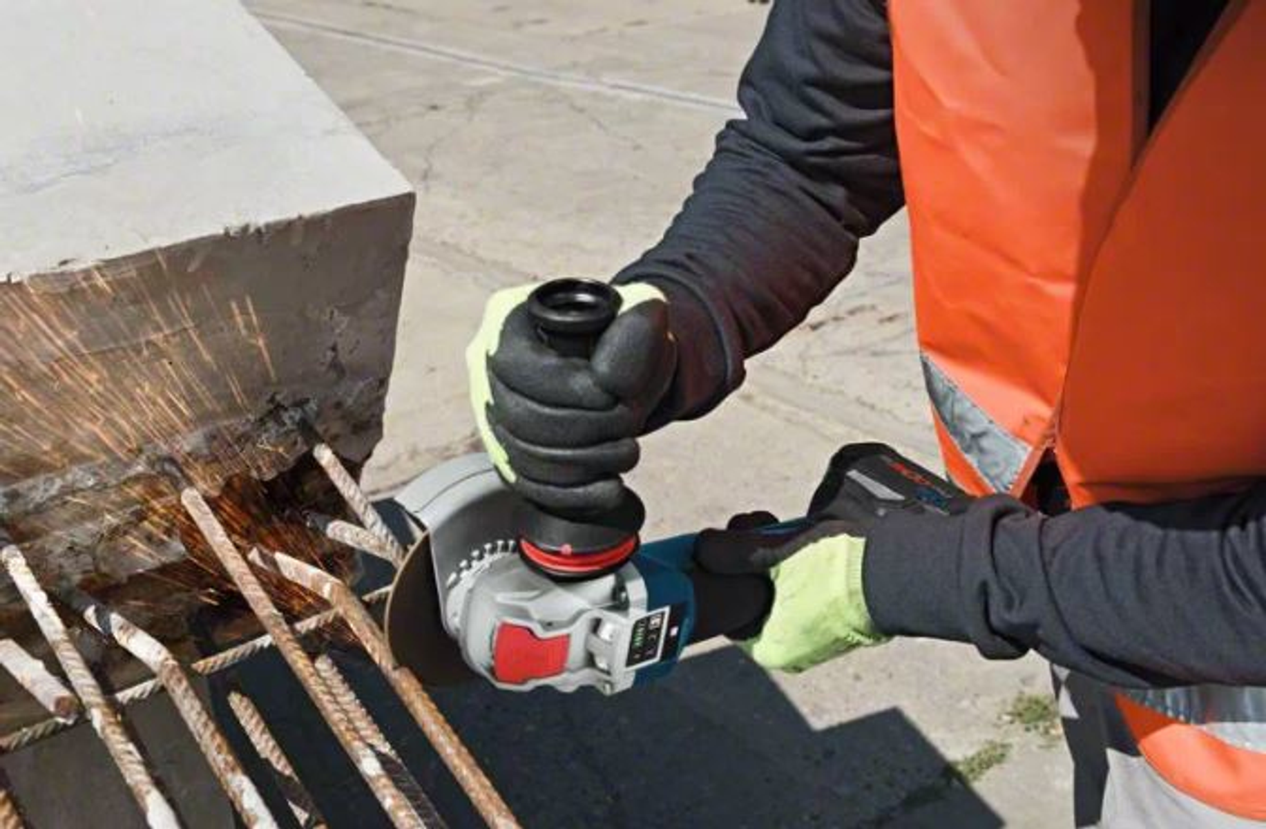 Osoba używająca szlifierki do metalu, iskry, rękawice i kamizelka.