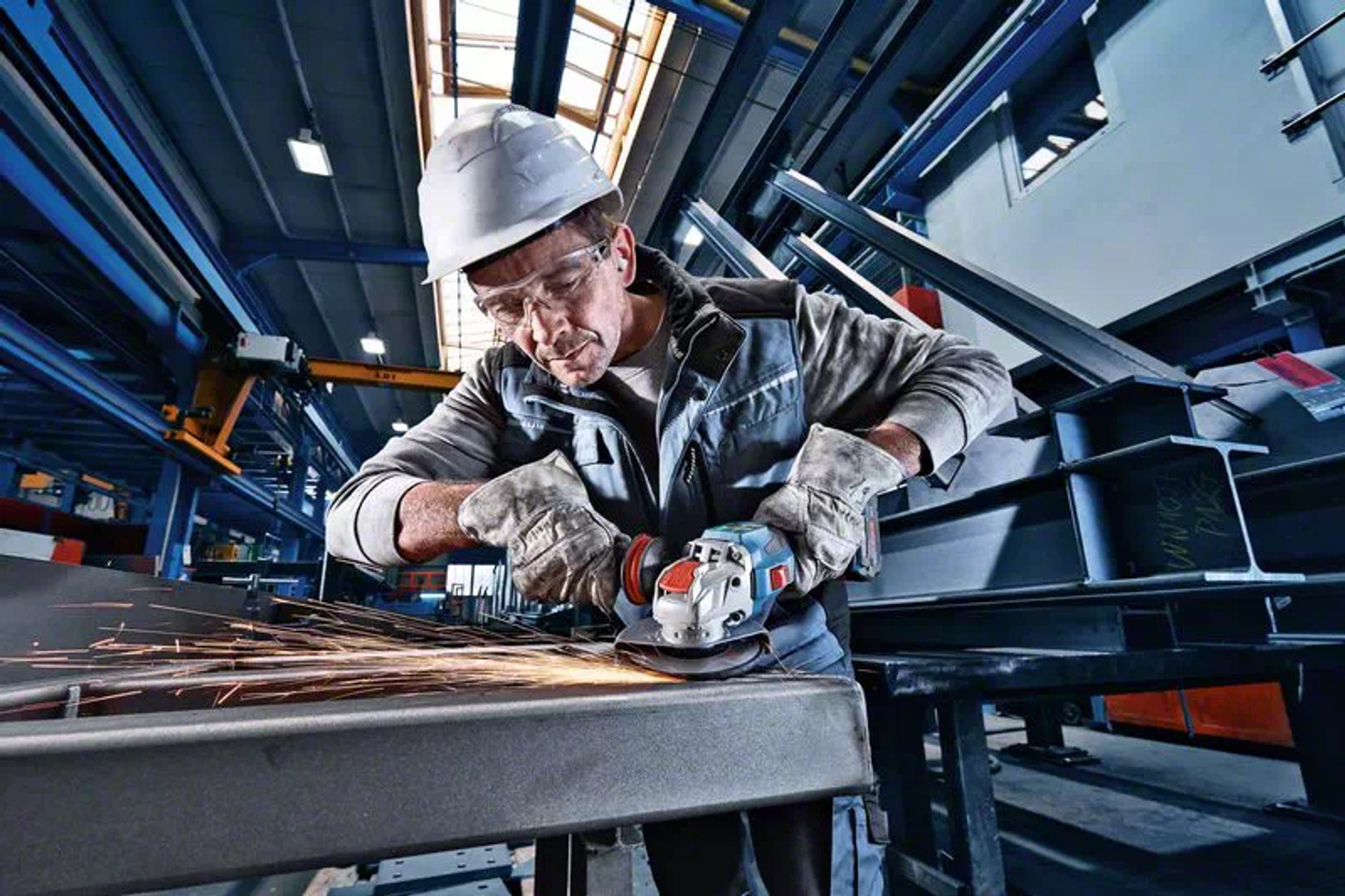 Robotnik używa szlifierki kątowej na metalu. Iskry lecą.