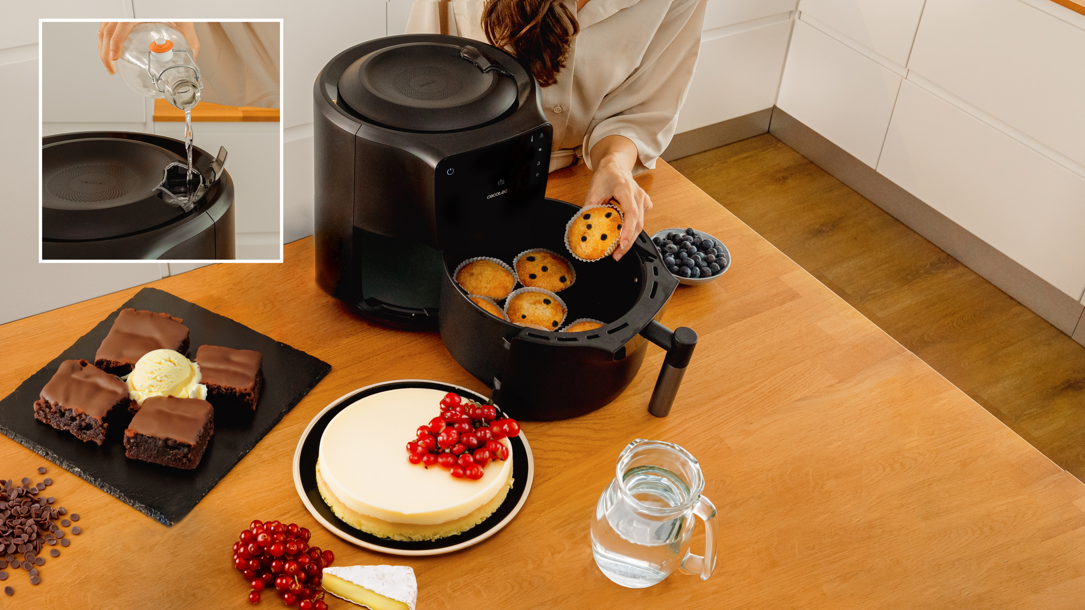 Una freidora de aire con comida y agua vertiéndose en ella. Incluye muffins, pastel y fruta.