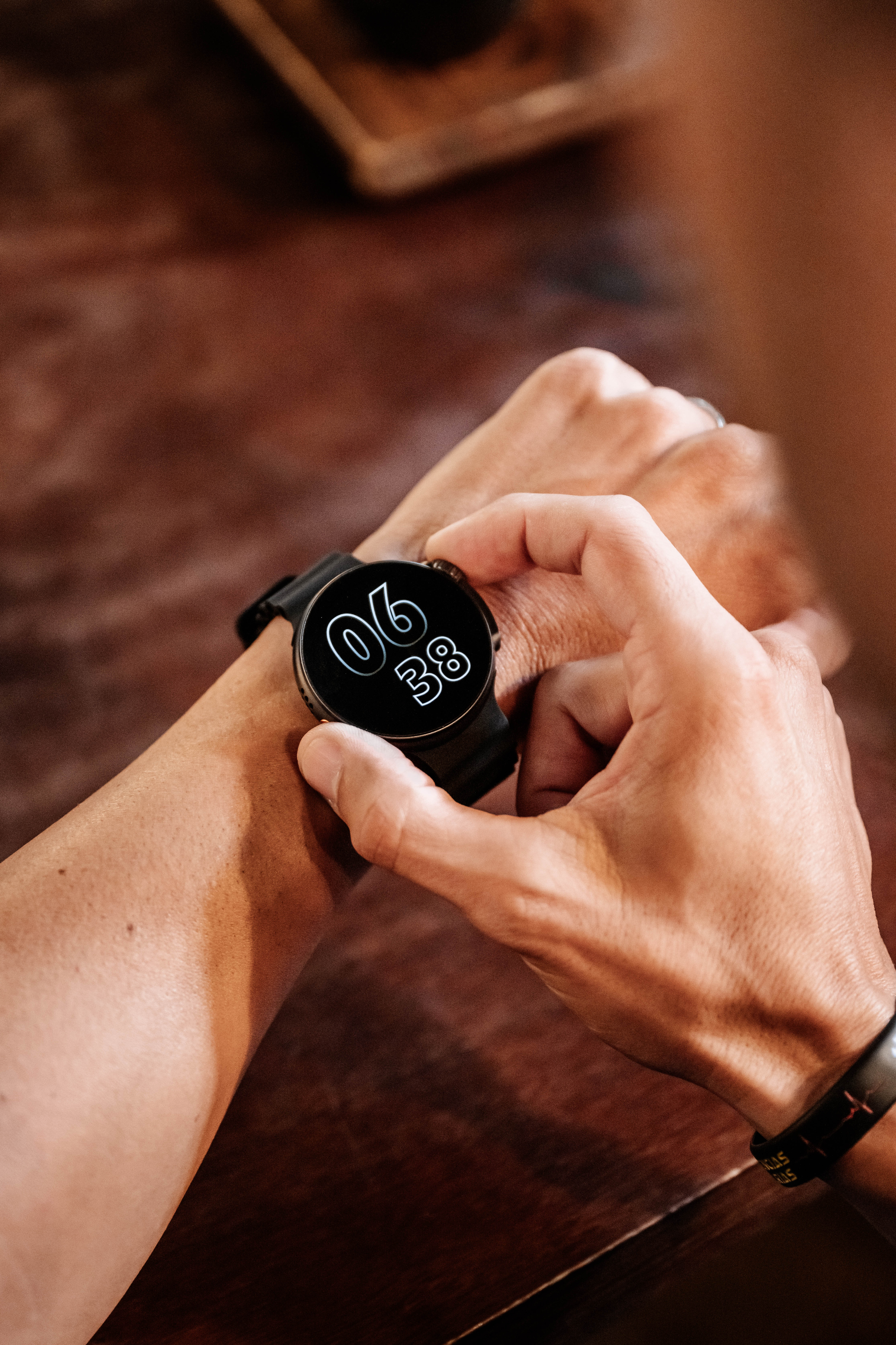 Muñeca de una persona con un reloj inteligente que muestra la hora y ajustándolo.