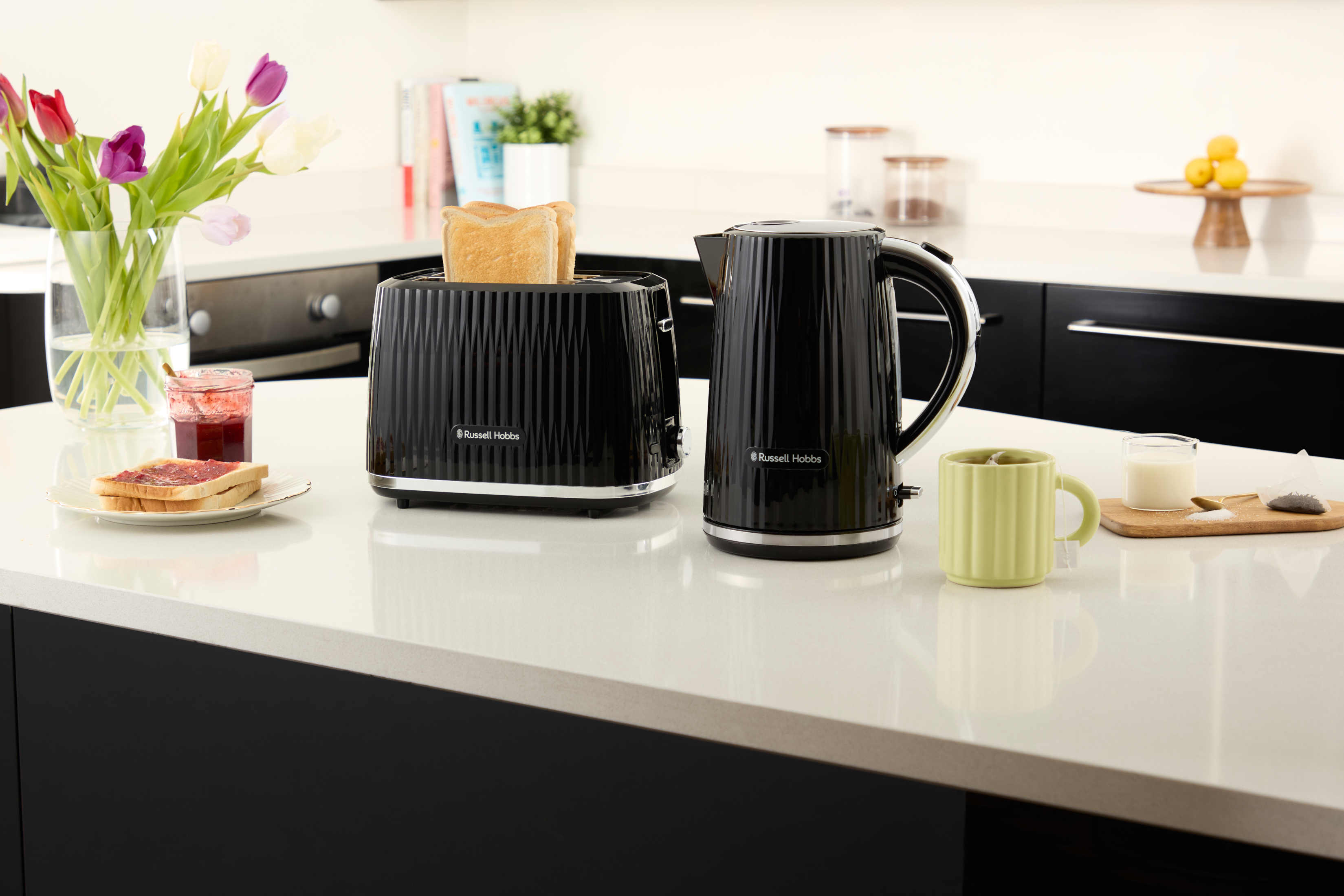 Blat kuchenny z tosterem, czajnikiem, tostem, dżemem i kubkiem z bukietem kwiatów.