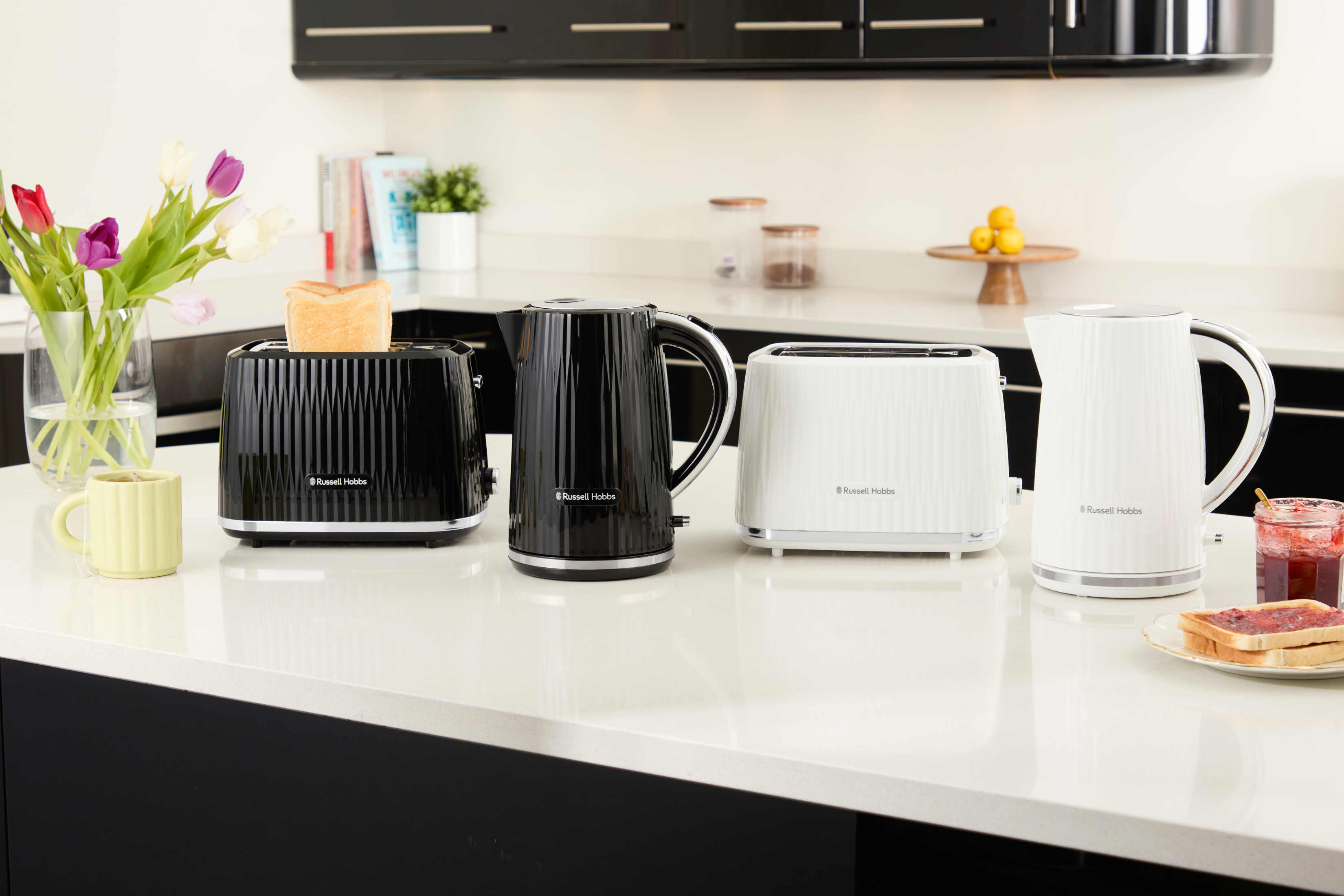 Cztery czarno-białe urządzenia Russell Hobbs na białym blacie.