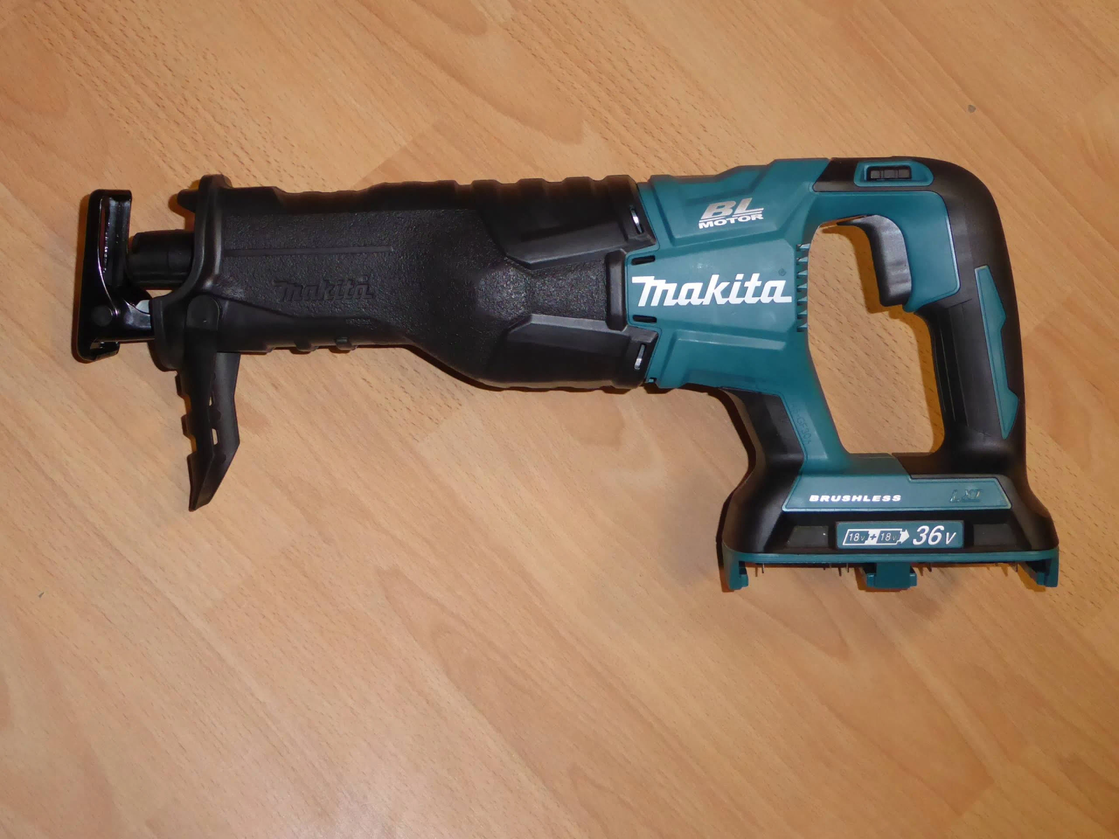 Una sierra recíproca Makita turquesa y negra sobre una superficie de madera.
