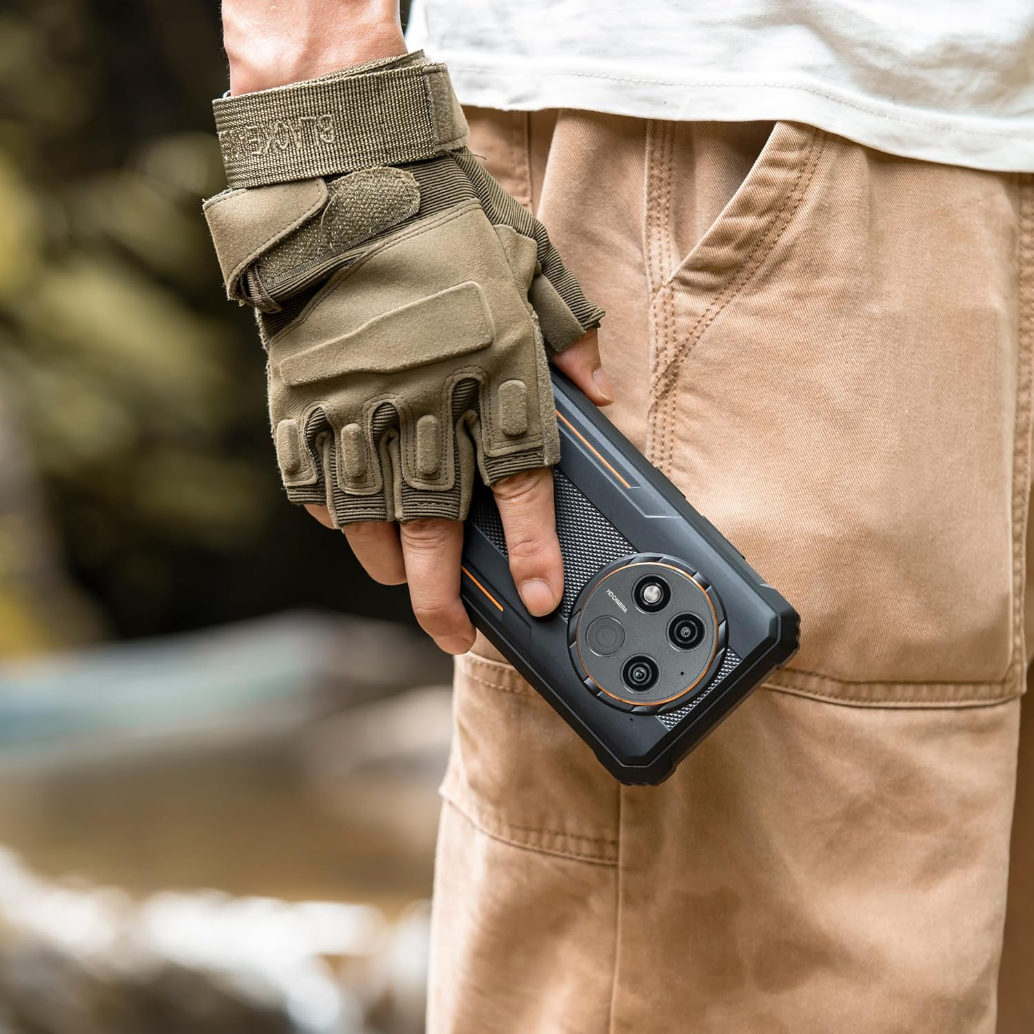 Person hält ein schwarzes, robustes Telefon mit einem Handschuh. Telefon hat drei Rückkameras.