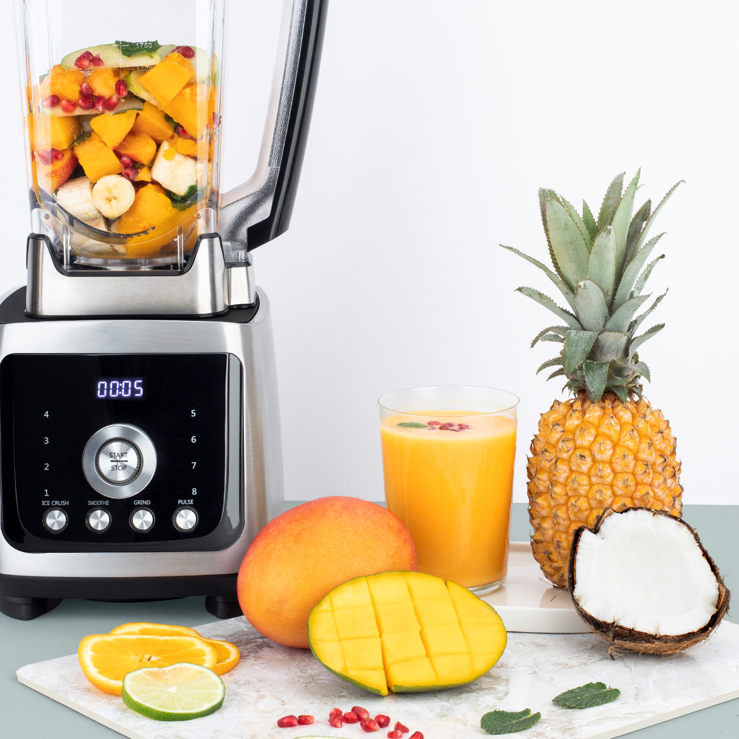 Blender ze składnikami takimi jak mango i ananas, ze szklanką soku i kokosem.