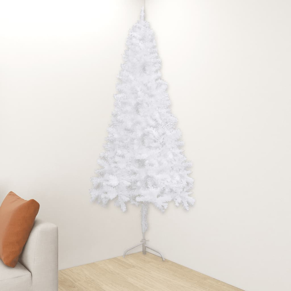 Weißer Weihnachtsbaum in einer Ecke. Er ist weiß und hat einen Ständer. Daneben steht eine Couch.