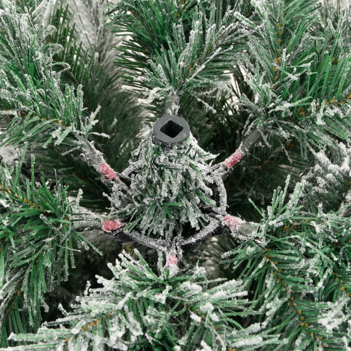 Nahaufnahme eines verschneiten Weihnachtsbaums. Grüne Nadeln sind teilweise mit Schnee bedeckt.