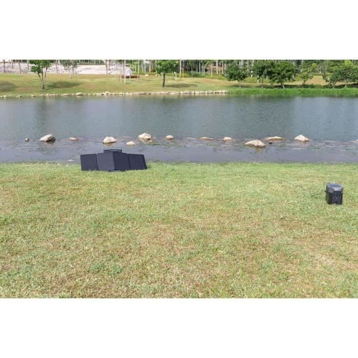 Jezioro z panelami słonecznymi i elektrownią na zielonej trawie.