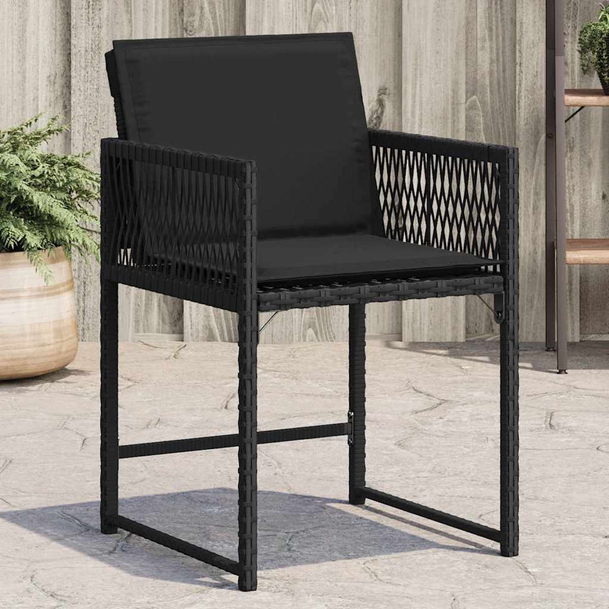 Una sedia da esterno in vimini nero con un cuscino nero.