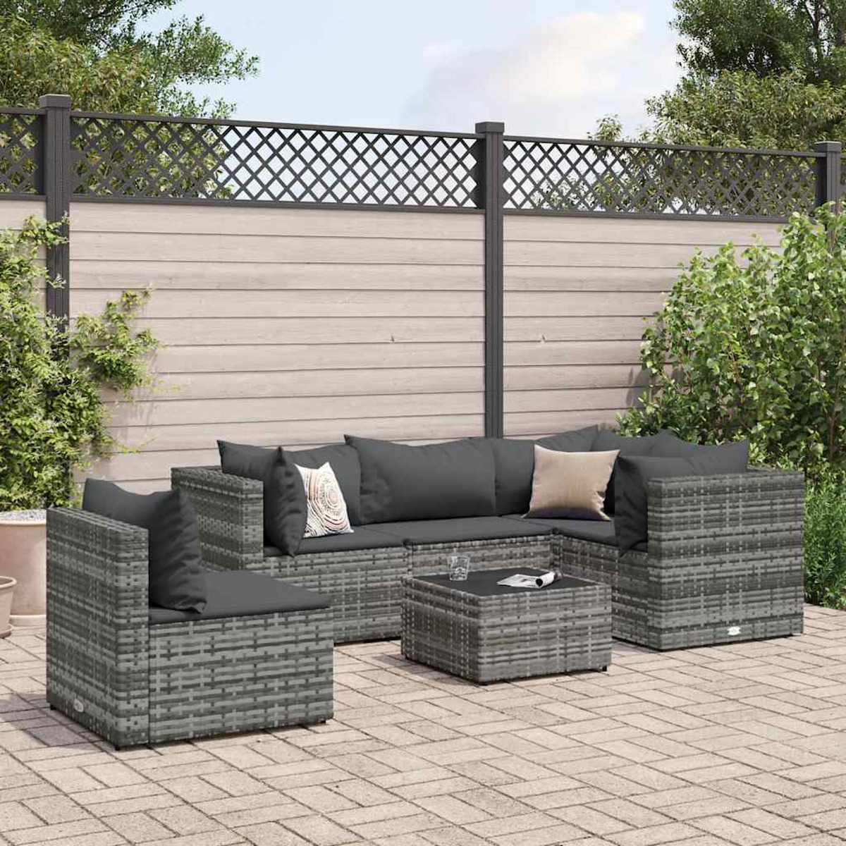 Set divano componibile da esterno in rattan grigio e tavolino su un patio.