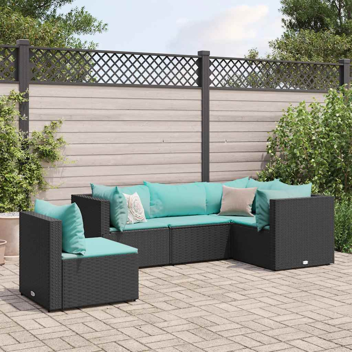 Set di sedute per esterni con mobili in vimini grigio scuro, cuscini turchese e staccionata in legno.