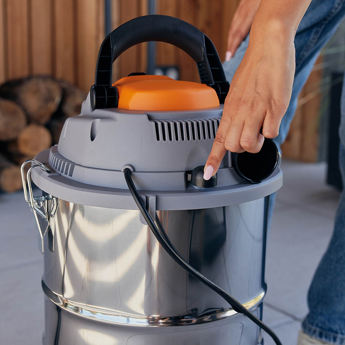 Ręka osoby naciskająca przycisk na odkurzaczu do pracy na mokro/sucho.