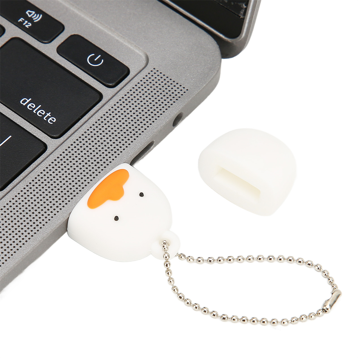 Ein weißer USB-Stick in Form eines Cartoon-Eis liegt neben einer Laptop-Tastatur.