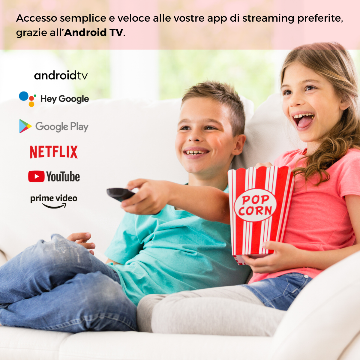 Due bambini su un divano. Un ragazzo tiene un telecomando, una ragazza popcorn. Loghi Android TV.