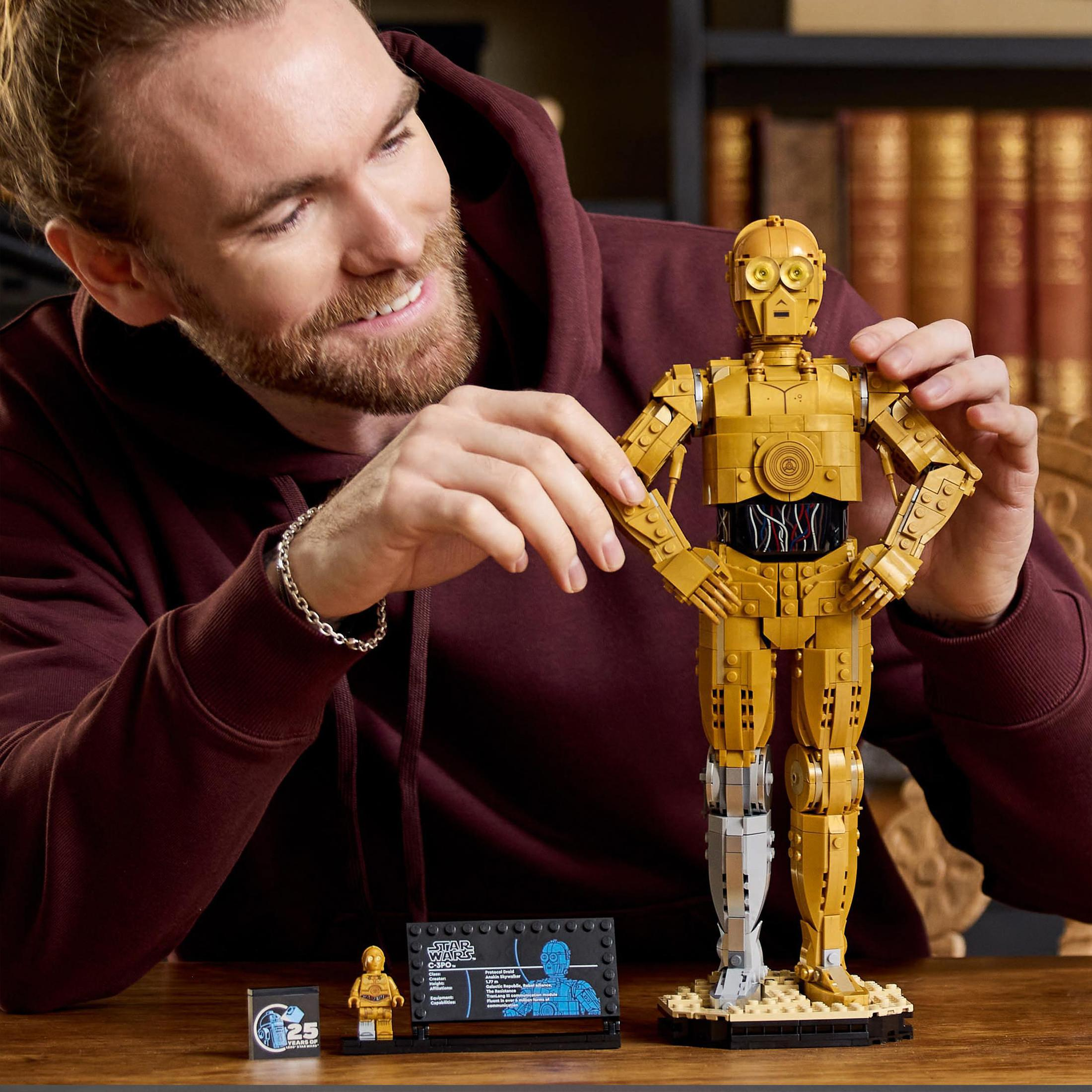 Mężczyzna trzymający model Lego C-3PO. Model C-3PO jest złoty. Obok znajduje się wyświetlacz ze szczegółami.