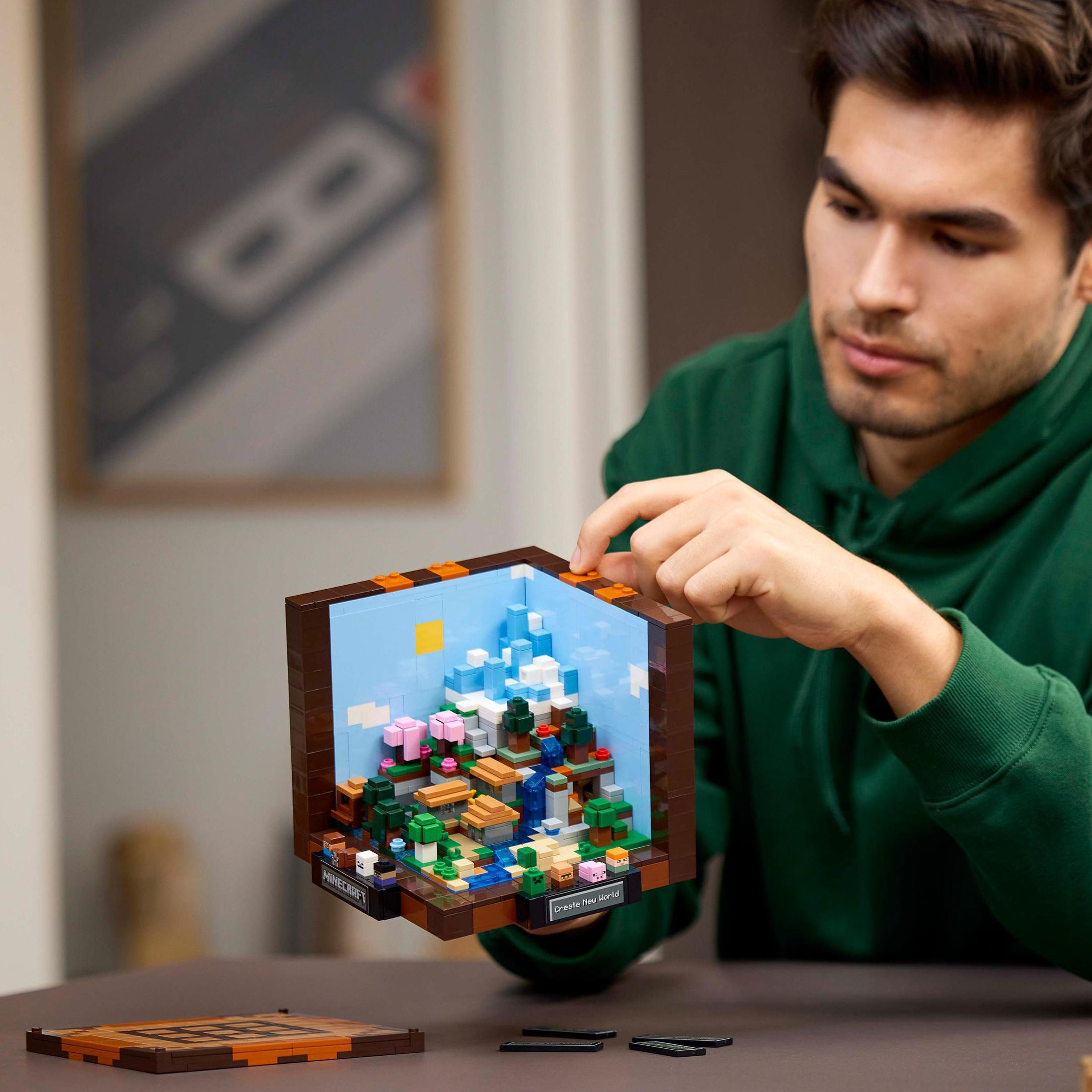 Mężczyzna składający dioramę Lego Minecraft. Diorama przedstawia kolorową scenę z Minecraft.