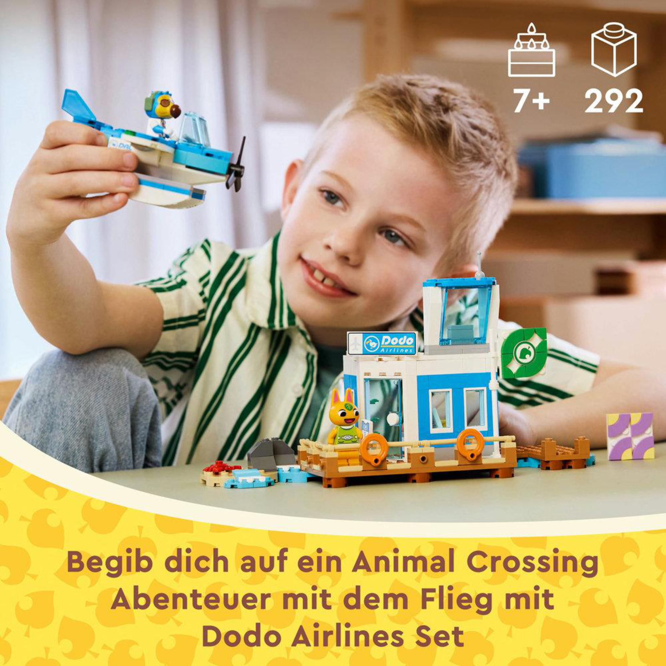 Ein Junge hält ein Lego-Flugzeug und ein Lego-Flughafen-Set mit einem Gebäude und einem kleinen Flugzeug.